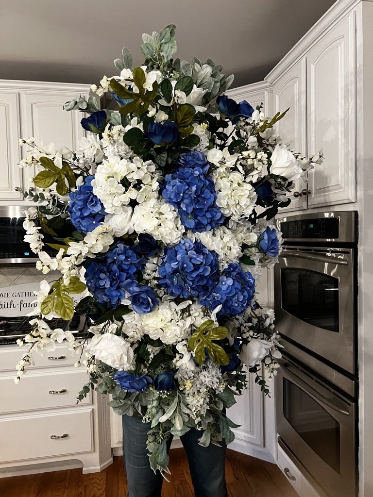 This beautiful large white and blue floral arrangement, which can be rented for an arch or wedding table, costs $500. We can also create a custom look for you.