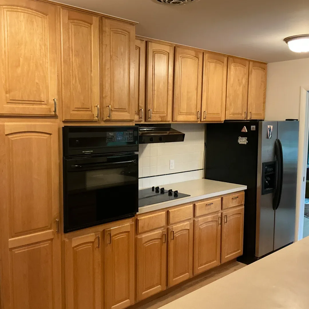 Kitchen awaiting remodel in Longmont, CO featuring crowded wall of honey stained cabinets and small black appliances with limited counter space