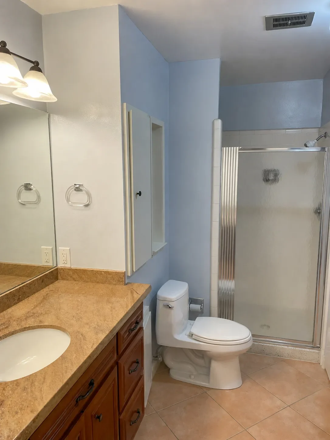 Bathroom in Superior, CO before remodel featuring outdated frosted glass shower and brown vanity countertop