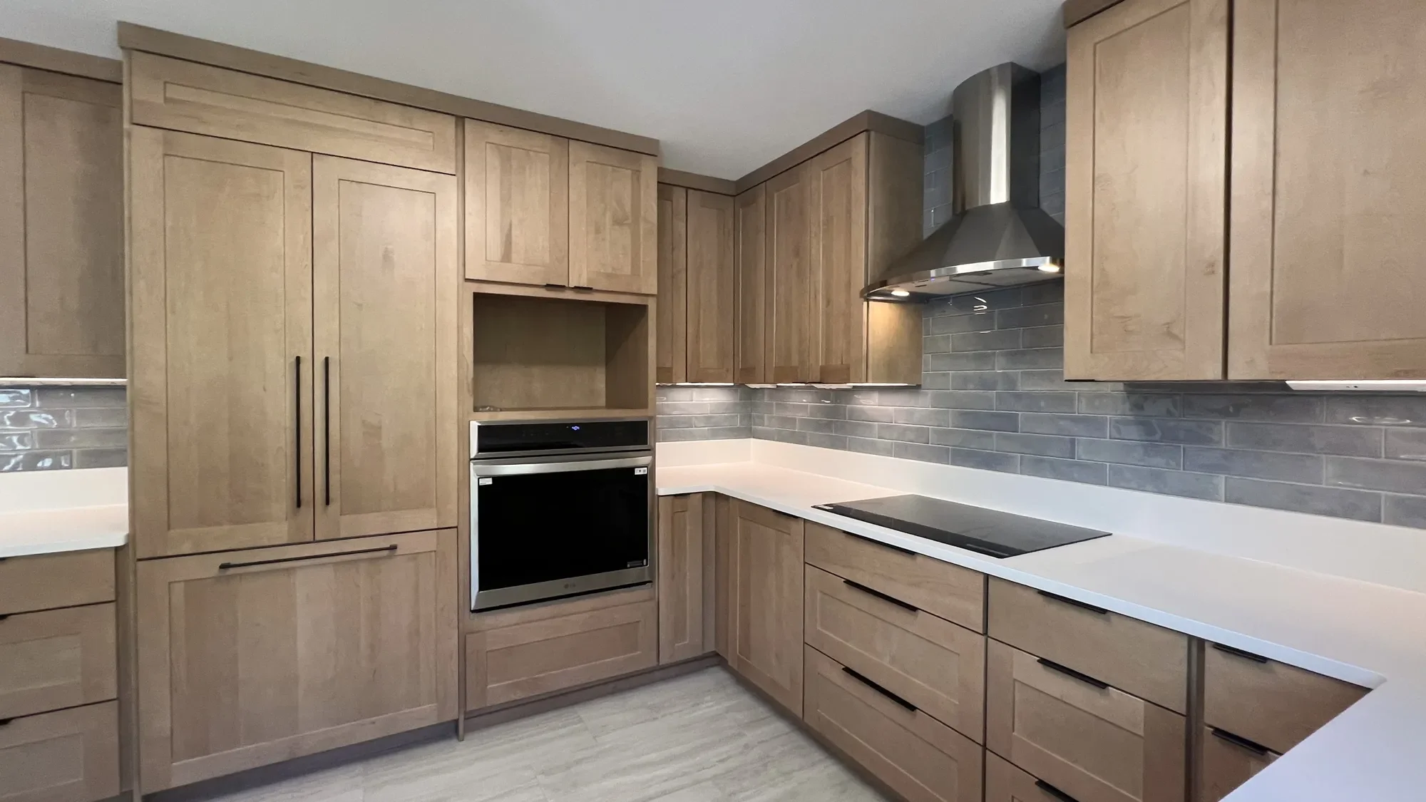 Banner view of contemporary craftsman style kitchen remodel in North Boulder, CO with custom shaker style oak conceal-panel cabinets, white quartz countertops, glass top inset induction stove, and stainless steel range hood