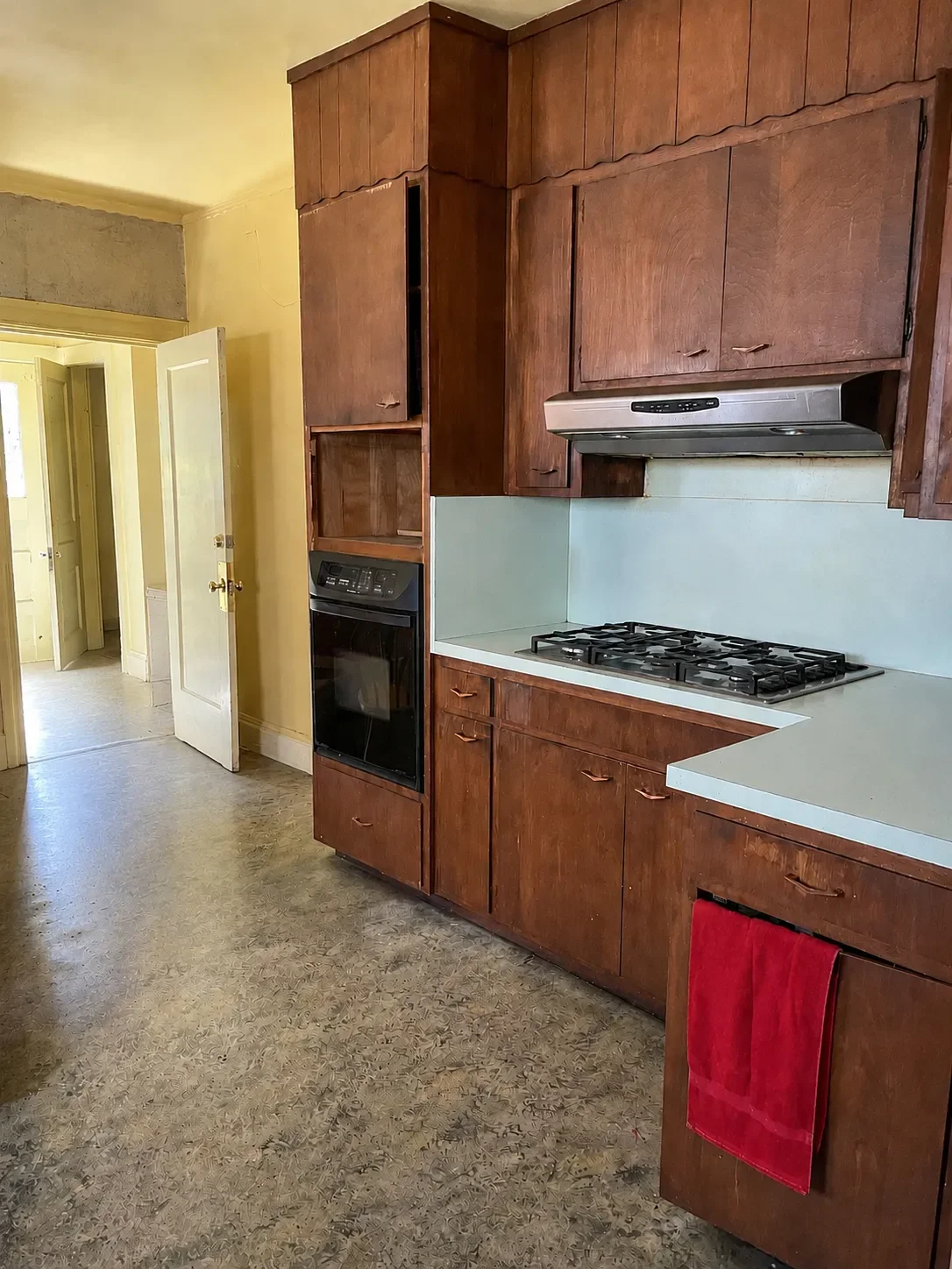 Interior of a dilapidated kitchen before beginning of remodeling project in Lafayette, CO featuring scalloped brown cabinets, yellow walls, and powder blue countertop and backsplash