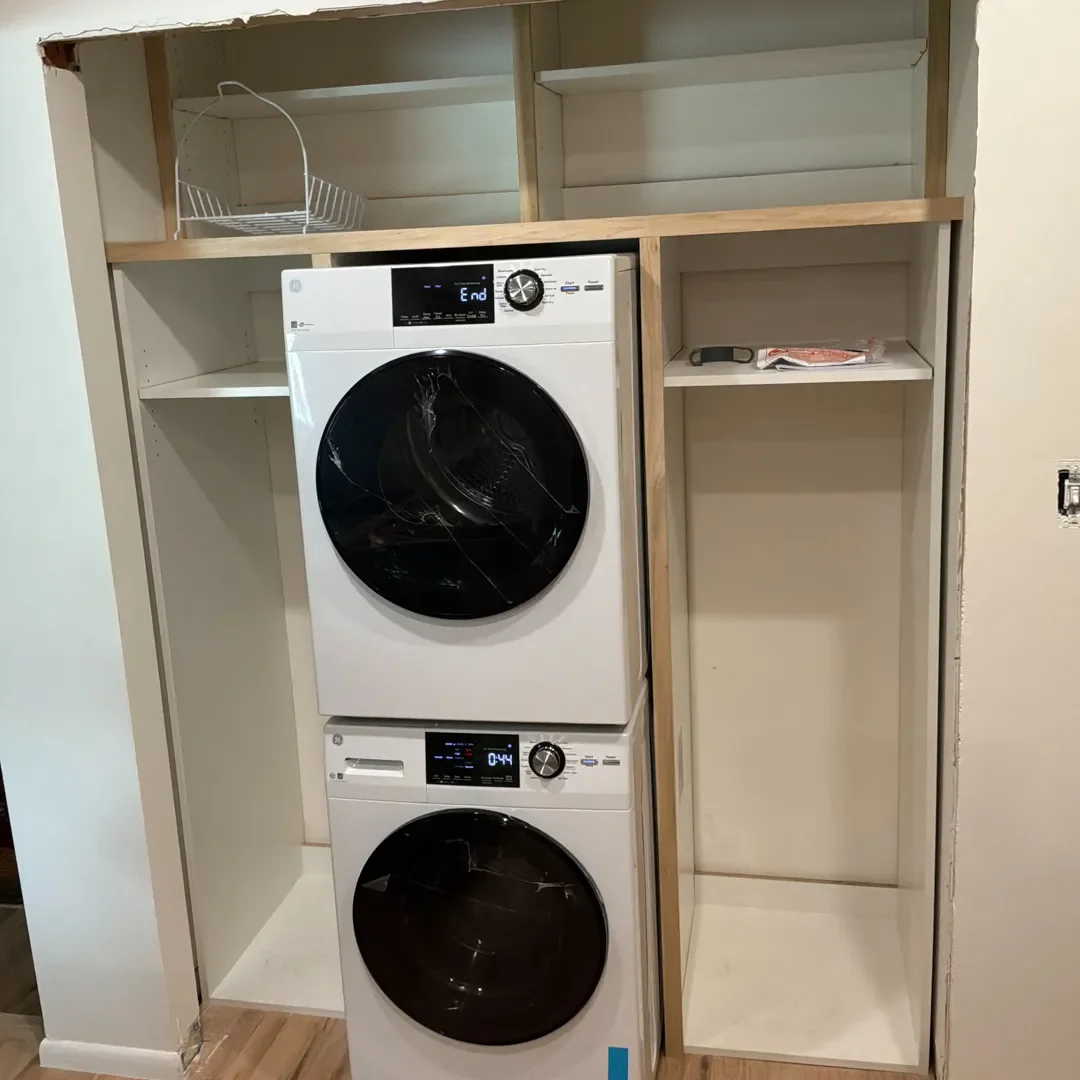 View of closet interior with new washer, dryer, and custom built shelving in an unfinished Longmont, CO home remodel by Downy Home Remodeling
