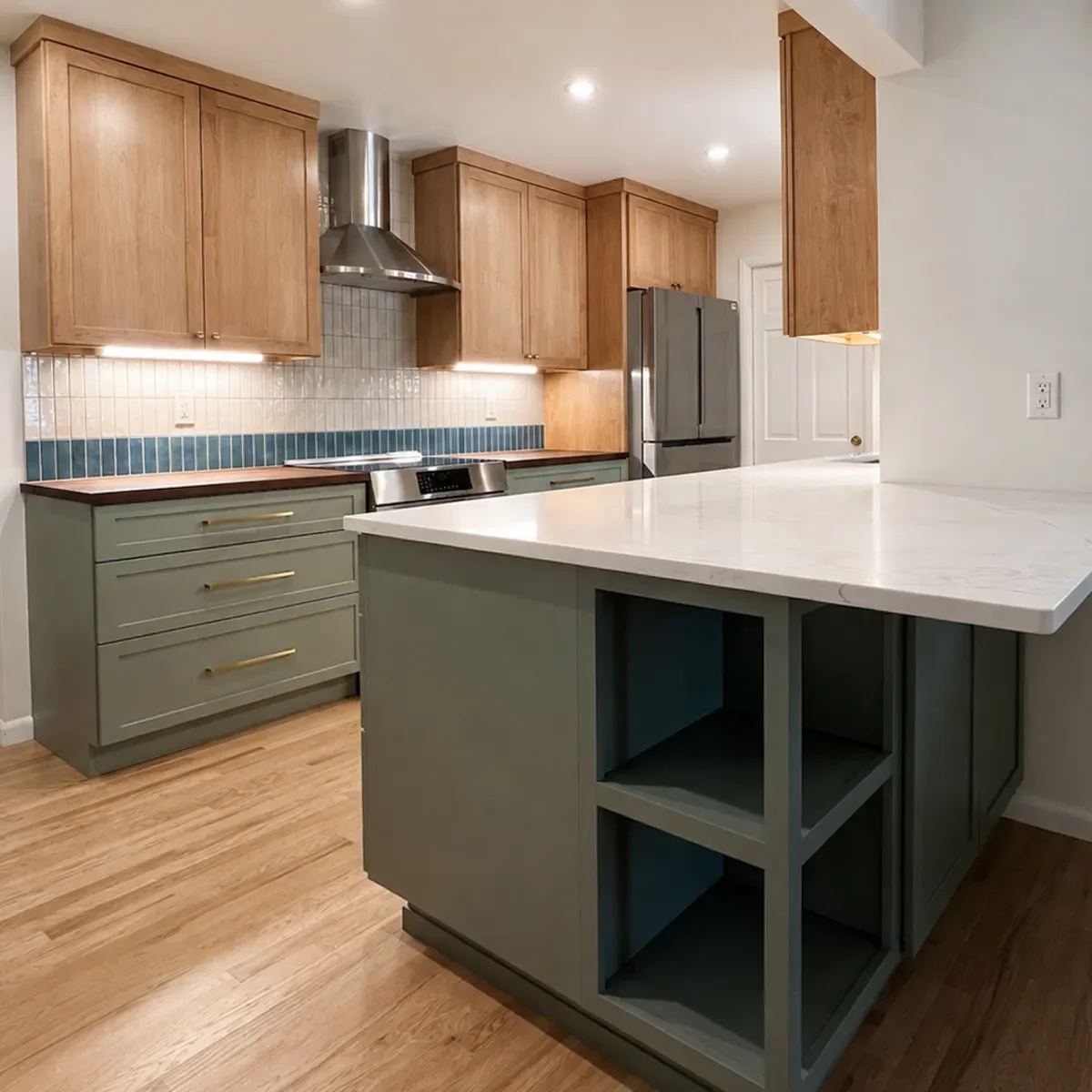 Longmont, CO completed mixed-material kitchen remodel featuring new extended peninsula with quartz countertop, open shelving, and barstool seating overhang, new red oak hardwood floors, maple upper cabinets, and earthy sage green lower cabinets