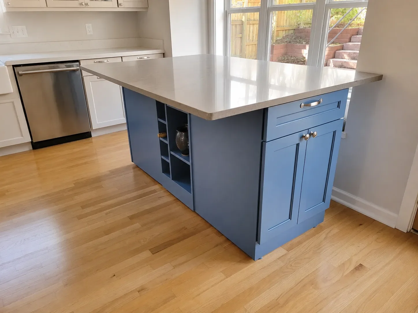 Custom kitchen island project in Superior, CO featuring blue mobile cabinets with cut out shelves, adjustable wheels, and a gray quartz countertop with 12 inch overhang for barstool breakfast nook seating
