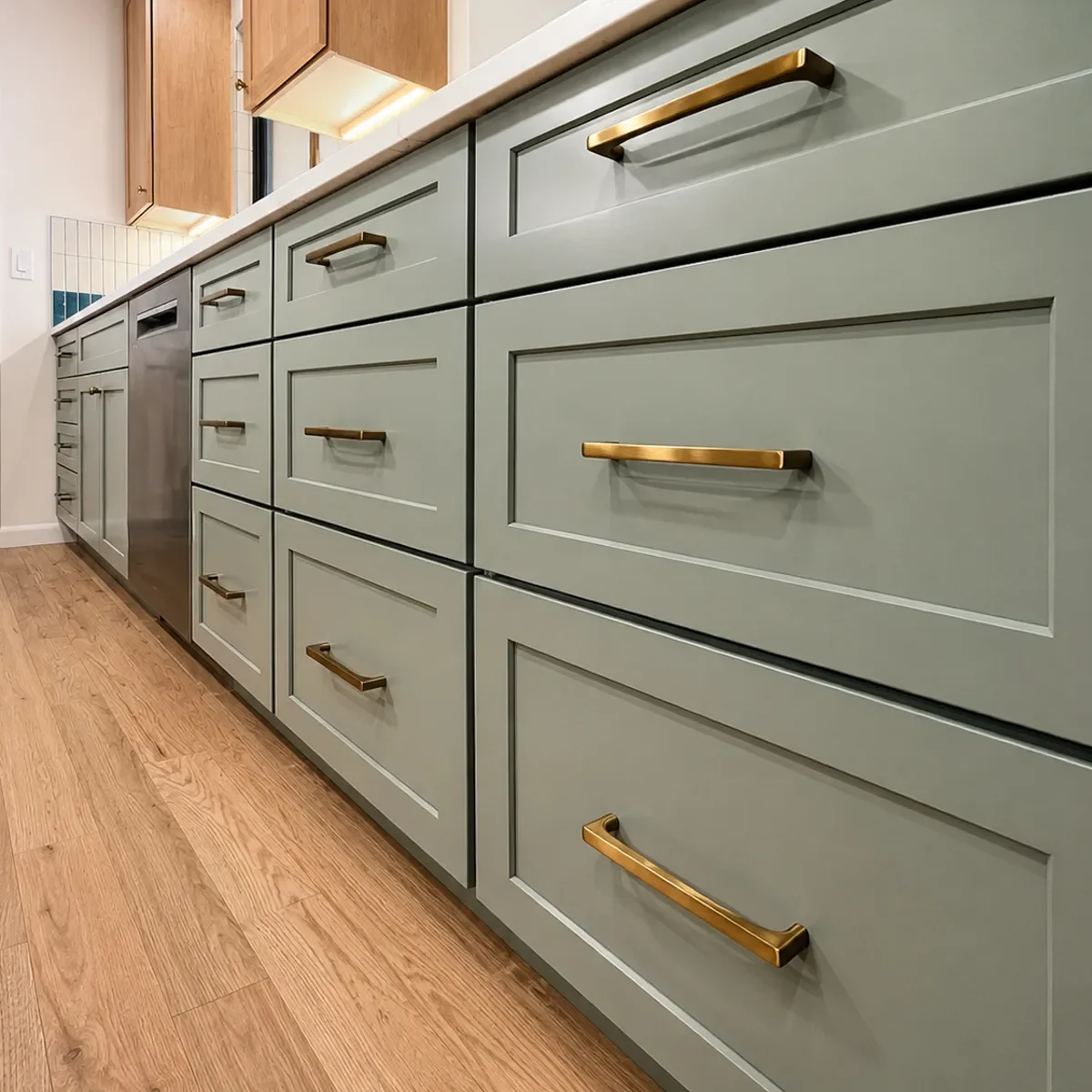 Close-up of shaker style eucalyptus green drawers with brass handles in a Longmont, CO kitchen remodel