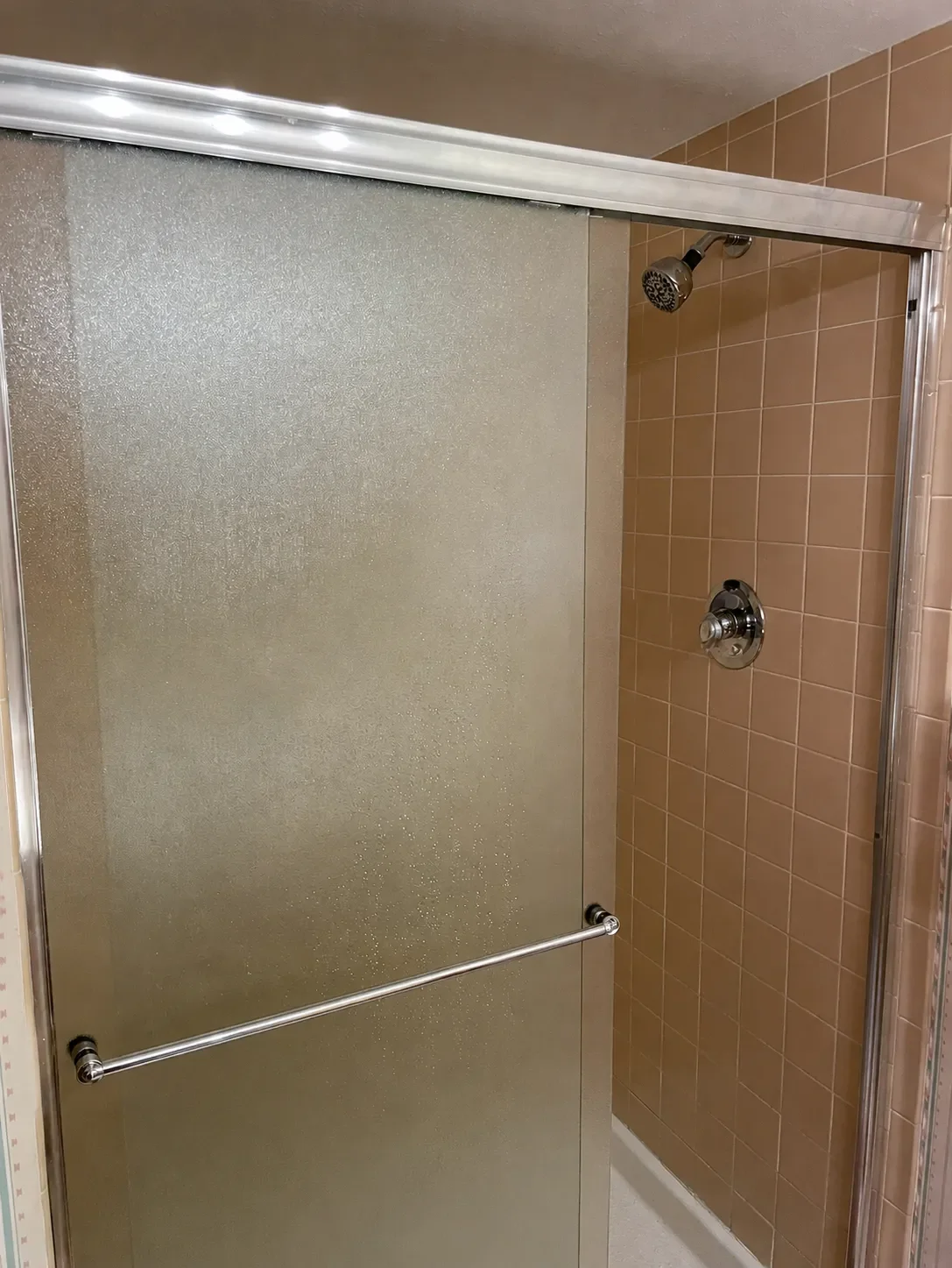 Niwot, CO dark basement bathroom remodel before picture featuring frosted glass shower door and 70's vintage brown tile color