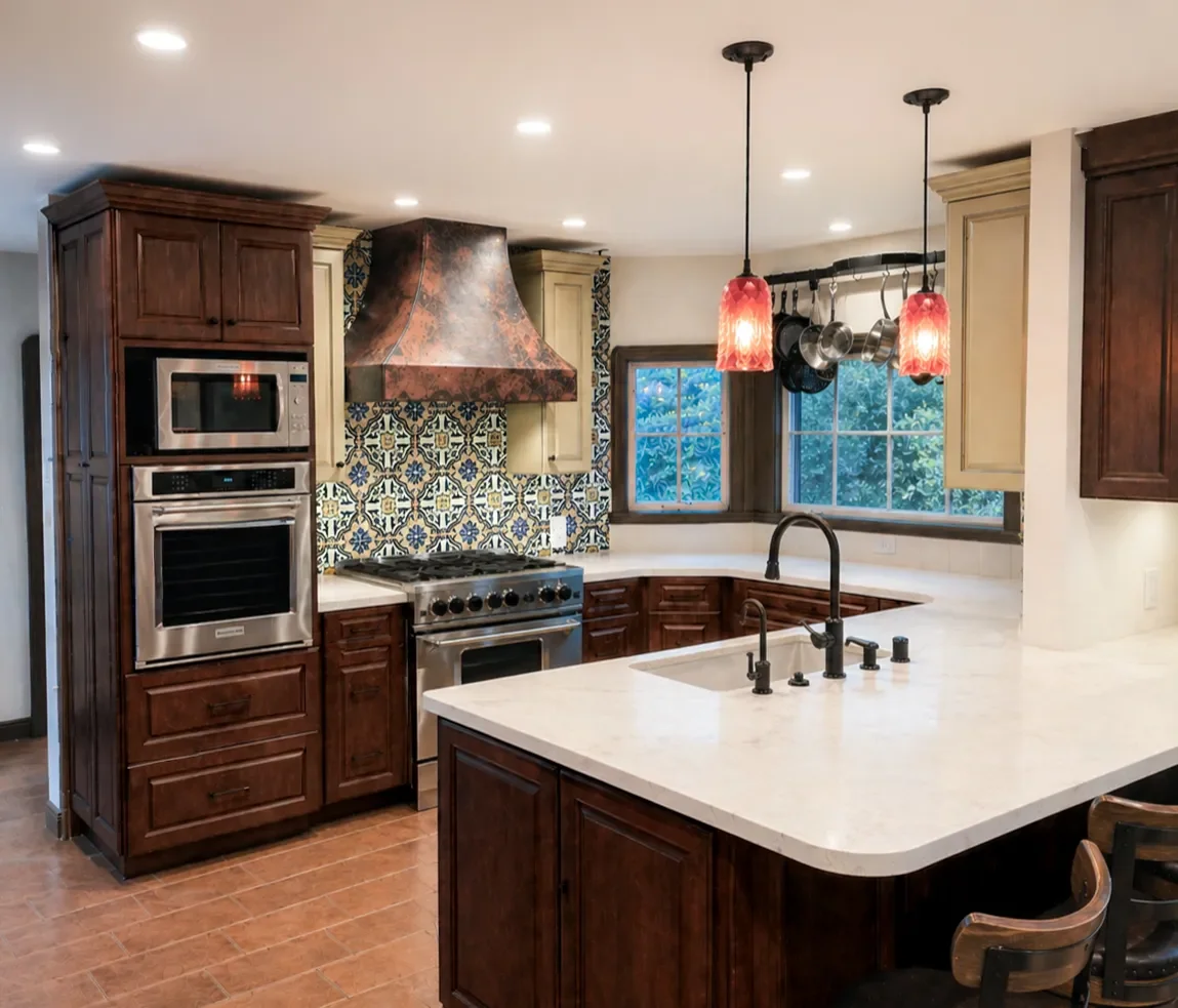 Modern kitchen with a center island, marble countertop, red pendant lights, stainless steel appliances, colorful tile backsplash, and wooden cabinets.