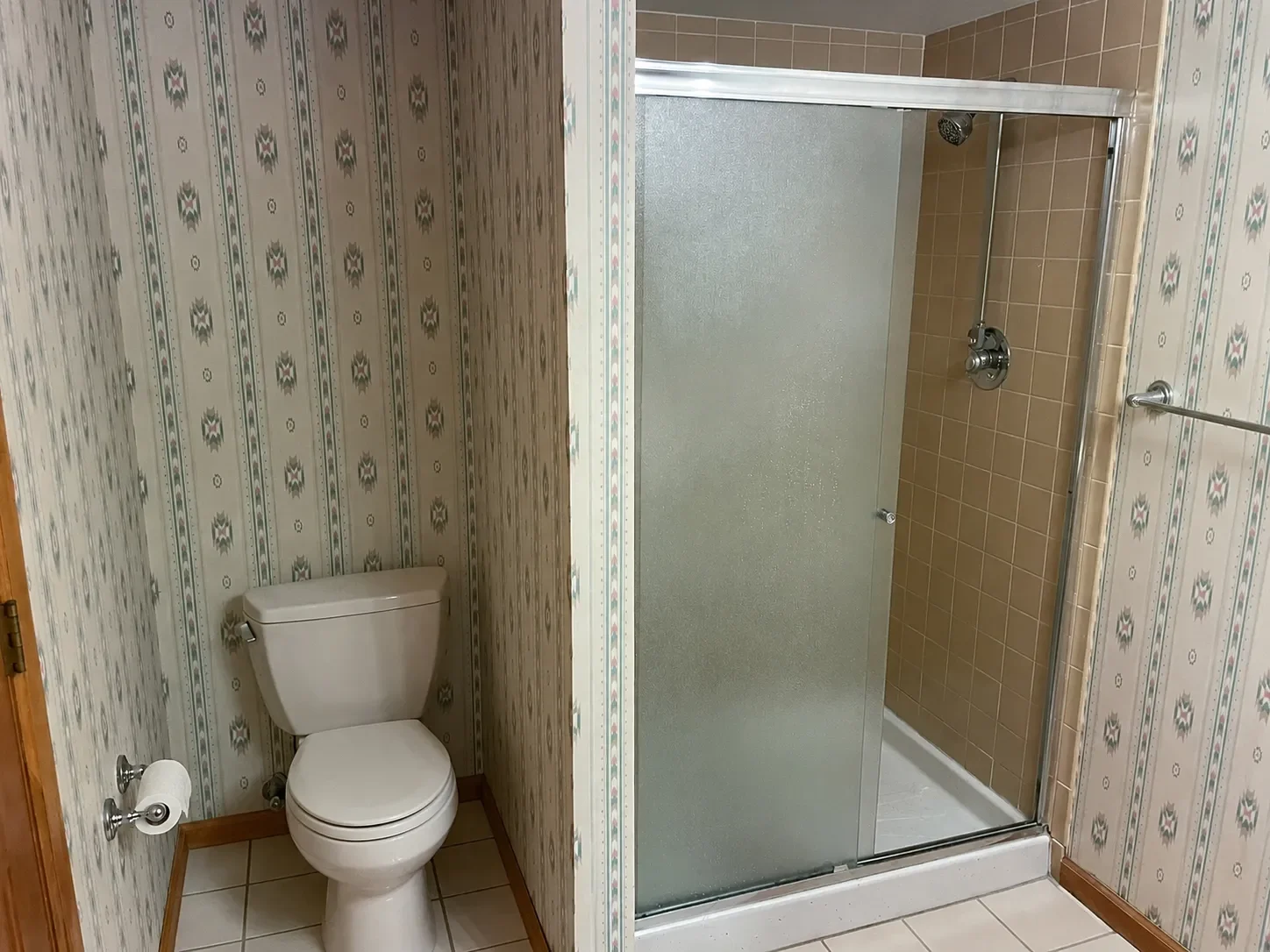 Bathroom in Niwot, CO before remodel featuring 70's southwestern style wallpaper and brown shower tiles