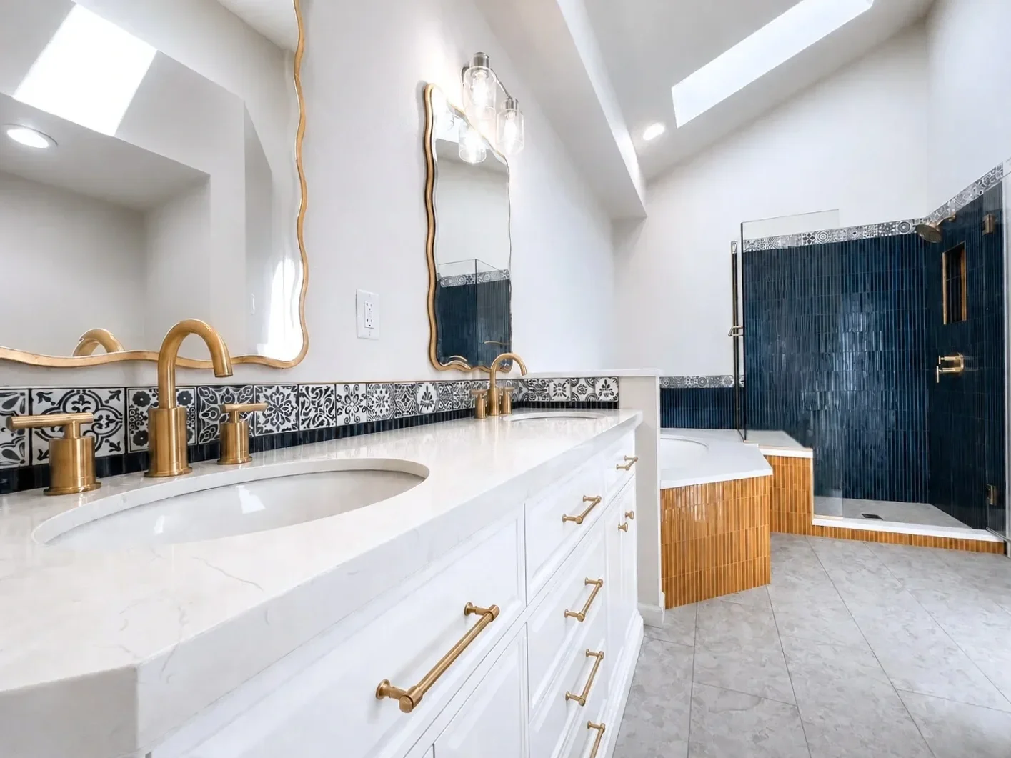 Contemporary Art Deco luxury master bathroom remodel in Gunbarrel, CO featuring vaulted ceilings, custom white vanity, white quartz countertop soaking tub, and walk-in shower with bench seating and bold blue and gold contrast tile