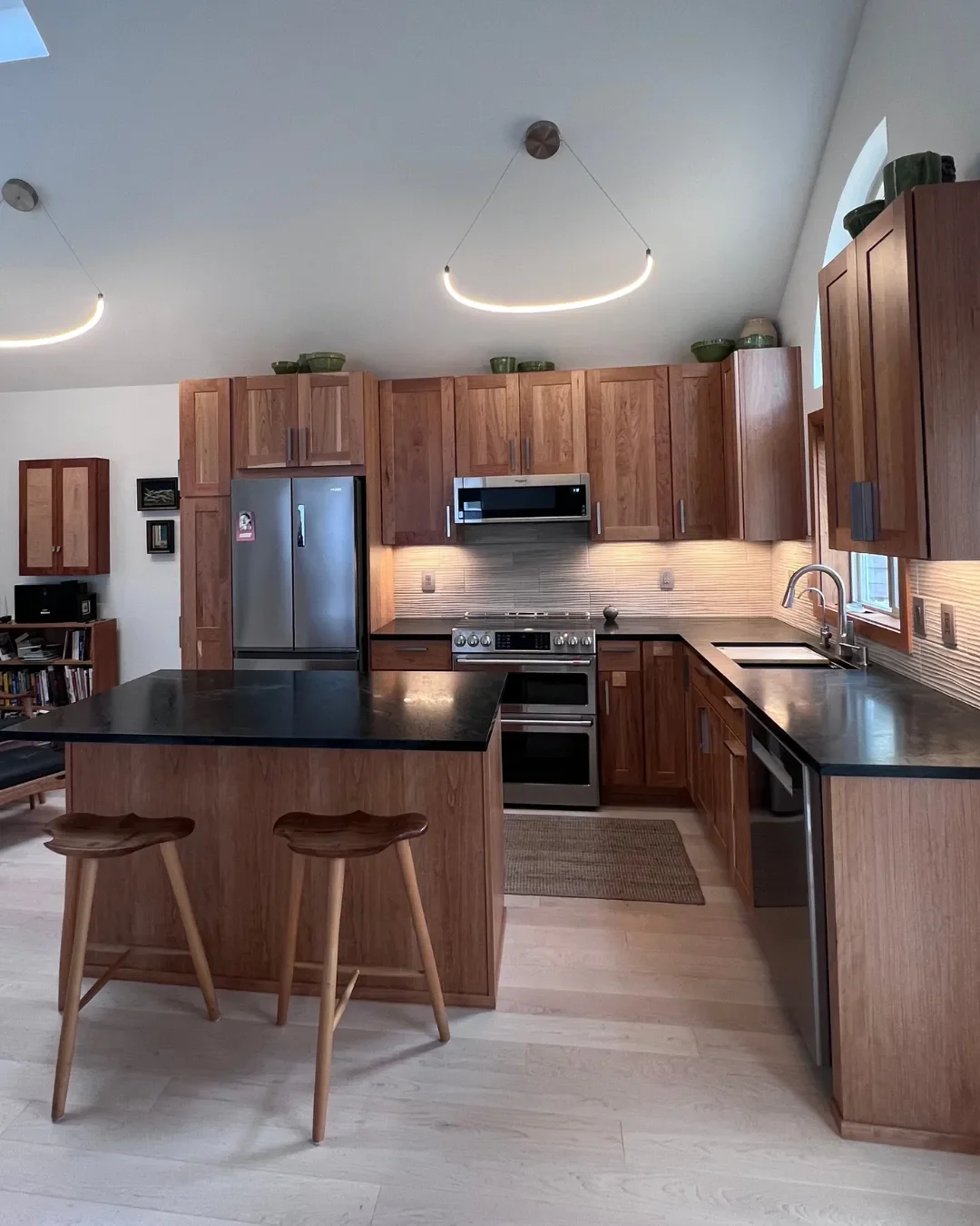 Remodeled contemporary craftsman style open concept kitchen with barstool seating, cherry wood cabinets, and LED undercabinet lighting