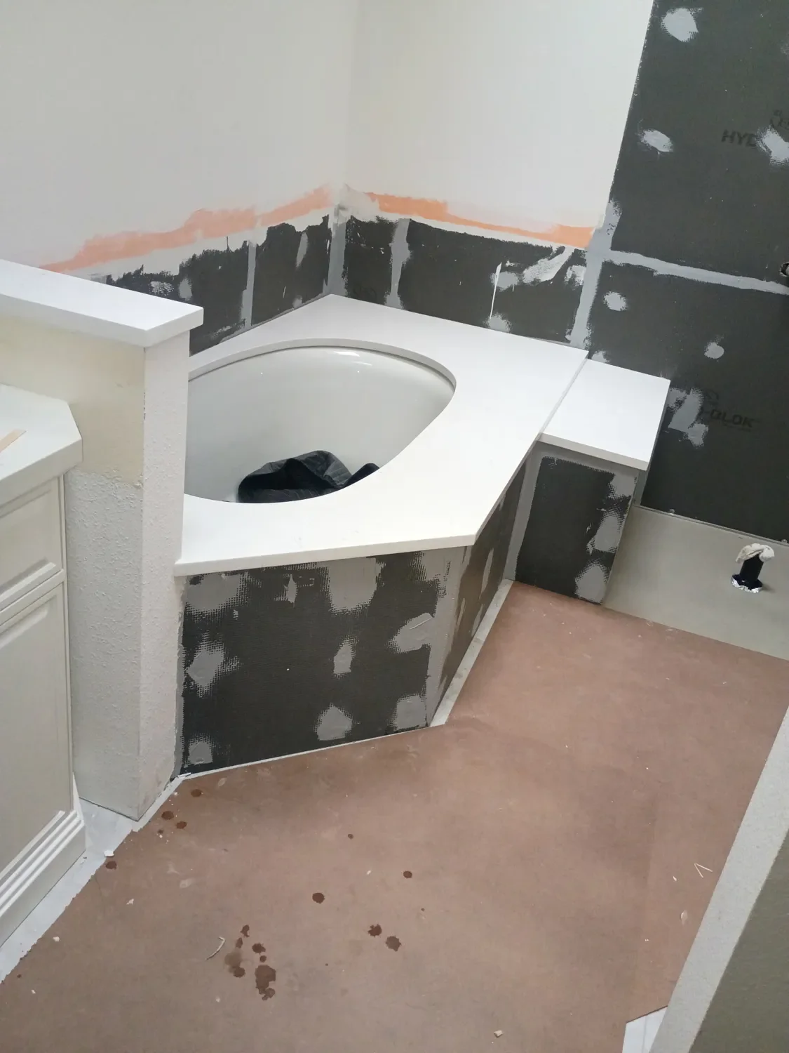 Custom templated quartz countertop over undermounted bathtub with shower bench extension in a Gunbarrel, CO master bathroom remodel in progress