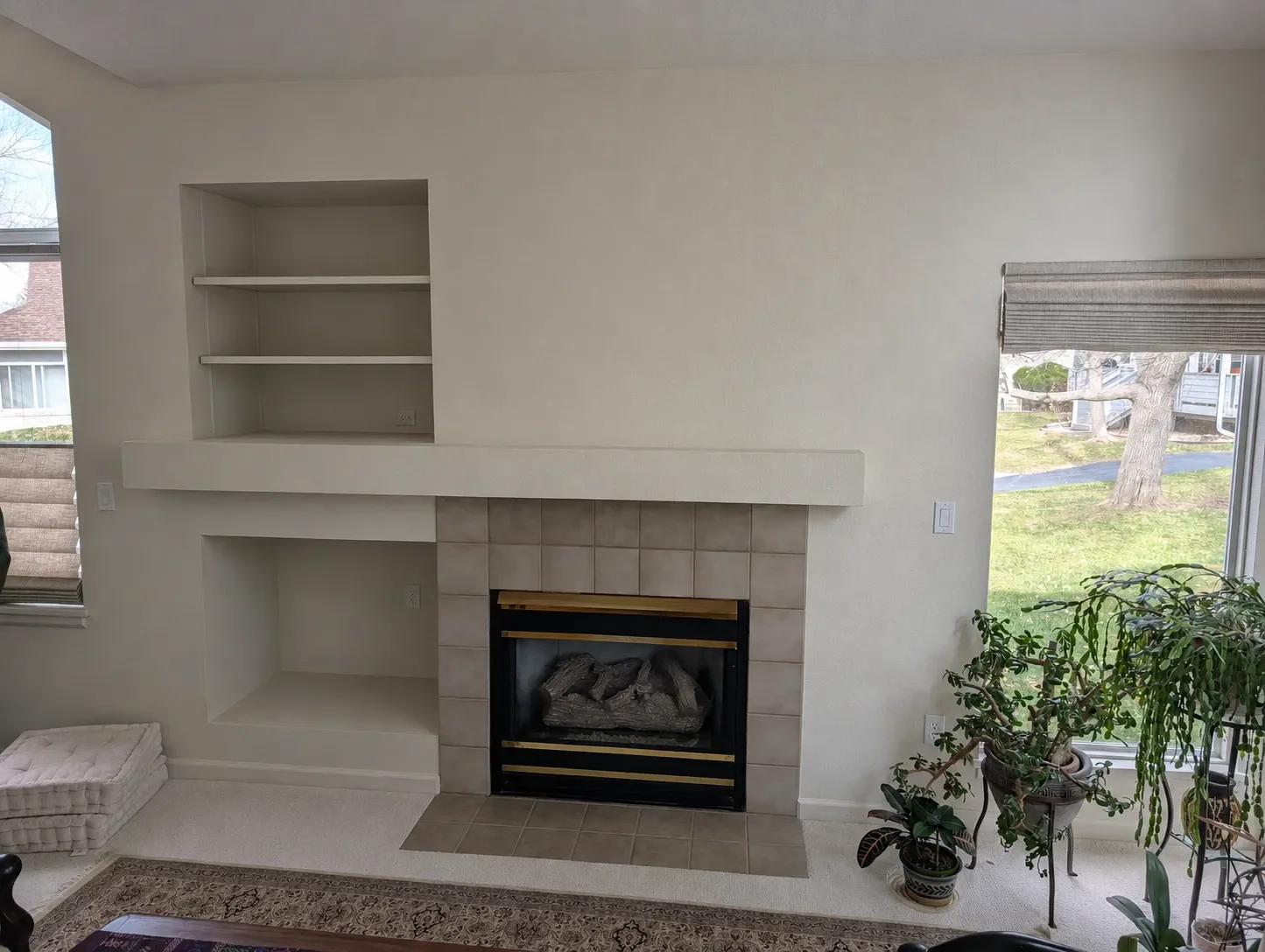 Before pic of gray tiled fireplace and white carpet in a Gunbarrel, CO living room awaiting renovation