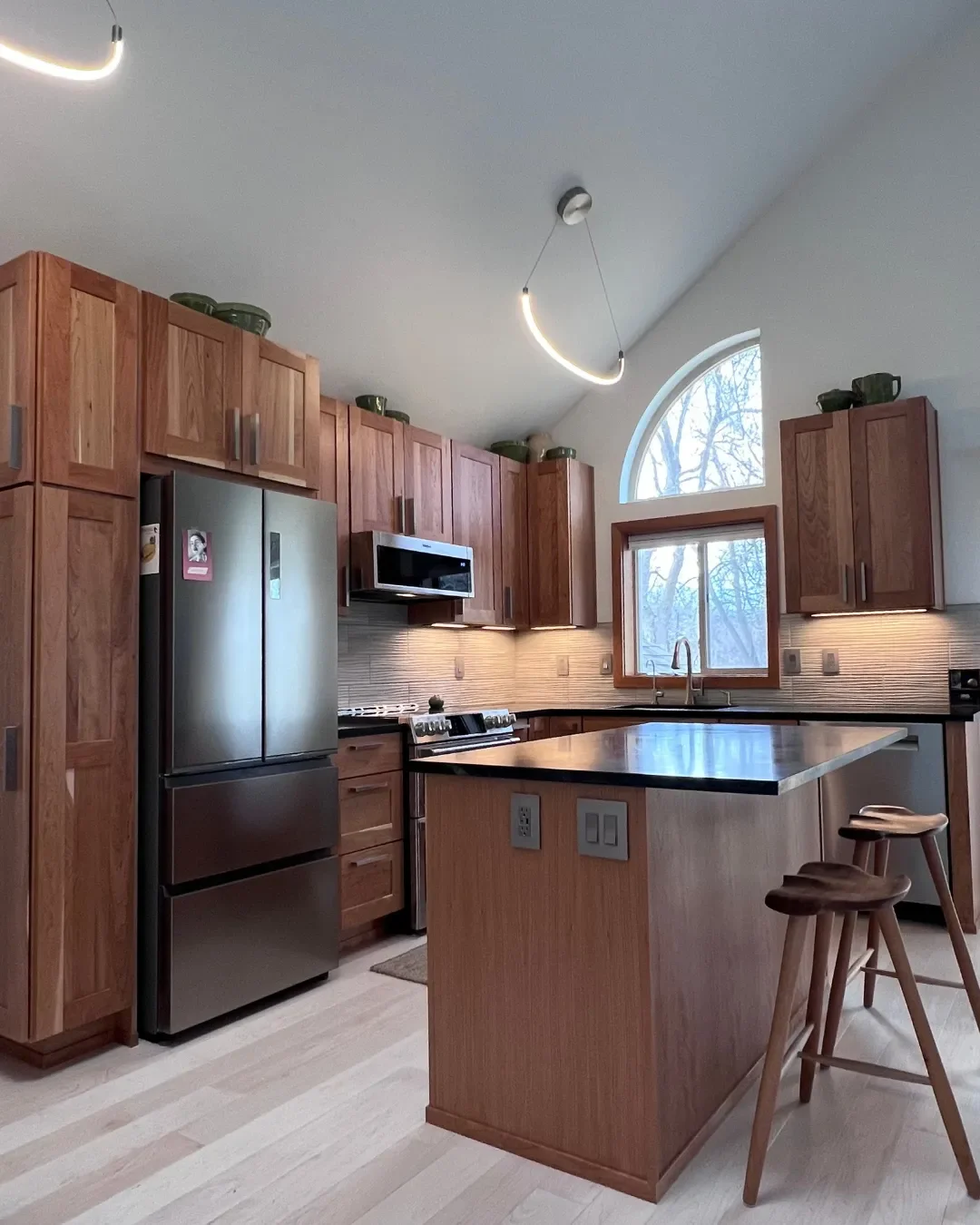 Contemporary craftsman style kitchen renovation in Newlands, North Boulder showcasing designer LED pendant lights hanging from vaulted ceilings and wavy textured cream backsplash lit by undercabinet LEDs