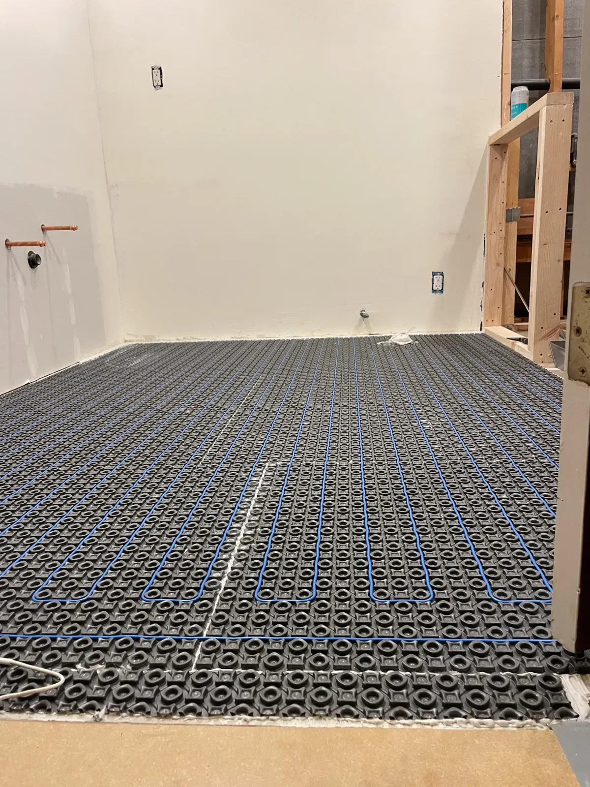 Heated floor cables woven into subfloor before tile installation in an unfinished bathroom remodel in Boulder, CO