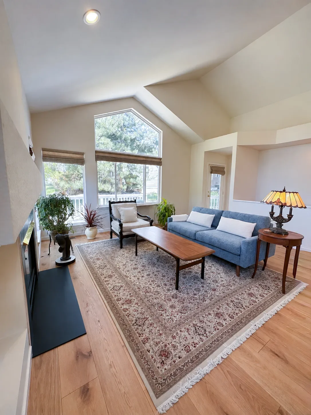 Furnished seating area in a newly remodeled Gunbarrel, CO living room featuring newly installed white oak hardwood floors, with craftsman style vaulted ceilings and windows overlooking new deck construction
