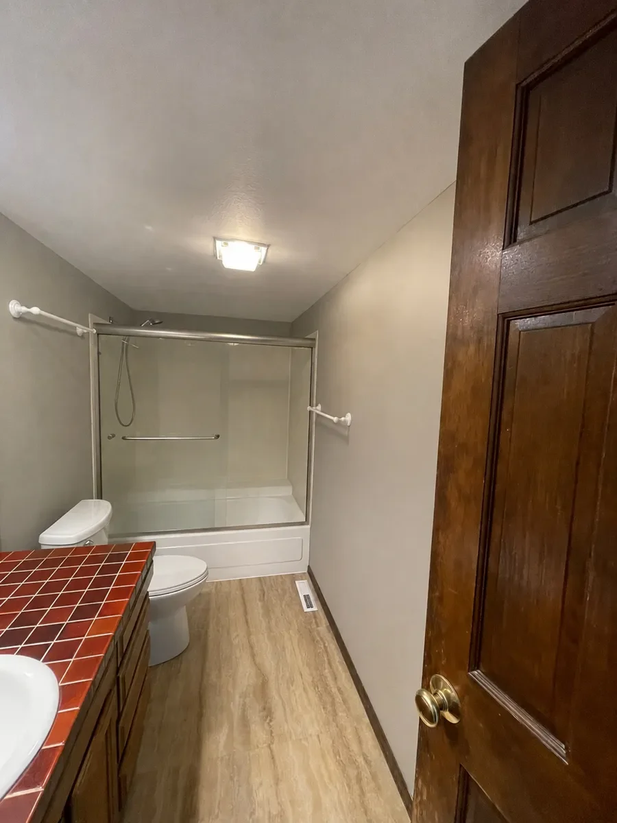 Bathroom in Table Mesa Boulder, CO with low ceiling, dim lighting, and dated dark wood vanity with red square tile countertop, before pic prior to remodeling