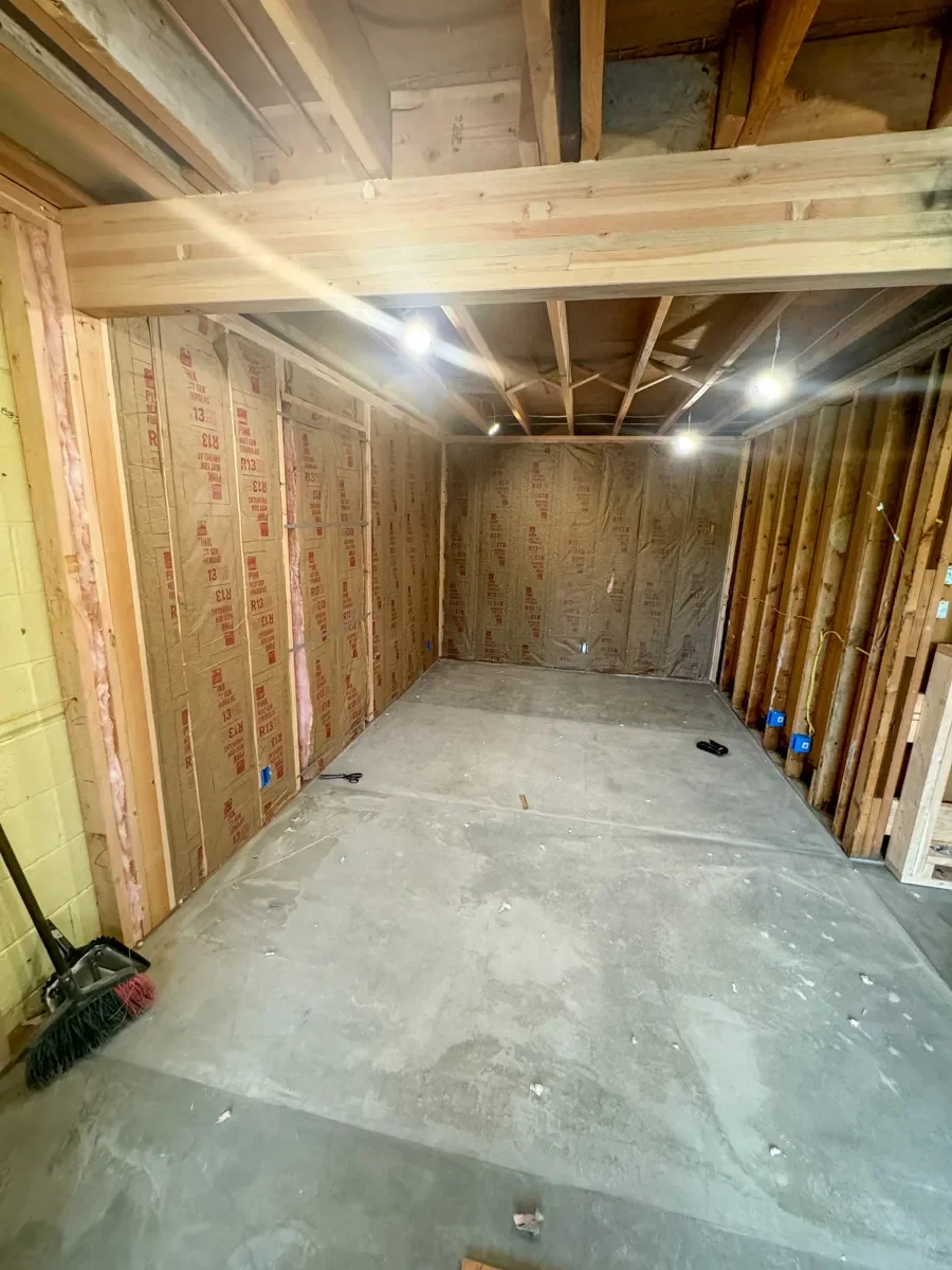 Boulder, CO basement remodel progress photo featuring freshly leveled concrete floors, insulation install, and exposed beam