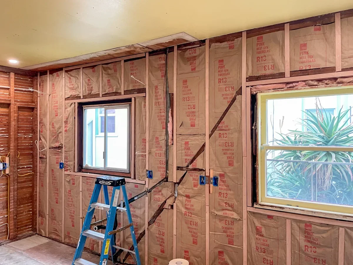 Lafayette, CO kitchen remodel under construction with exposed insulation and wiring. Walls are partially covered with Pink Next Gen Fiberglas insulation, and electrical boxes are installed.