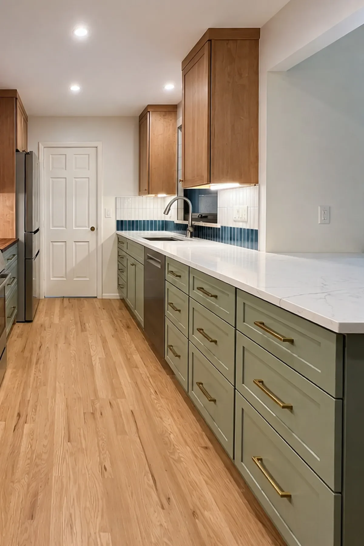 Remodeled kitchen in Longmont, CO featuring red oak hardwood floors, sage green lower cabinets, natural maple upper cabinets, and white quartz countertop