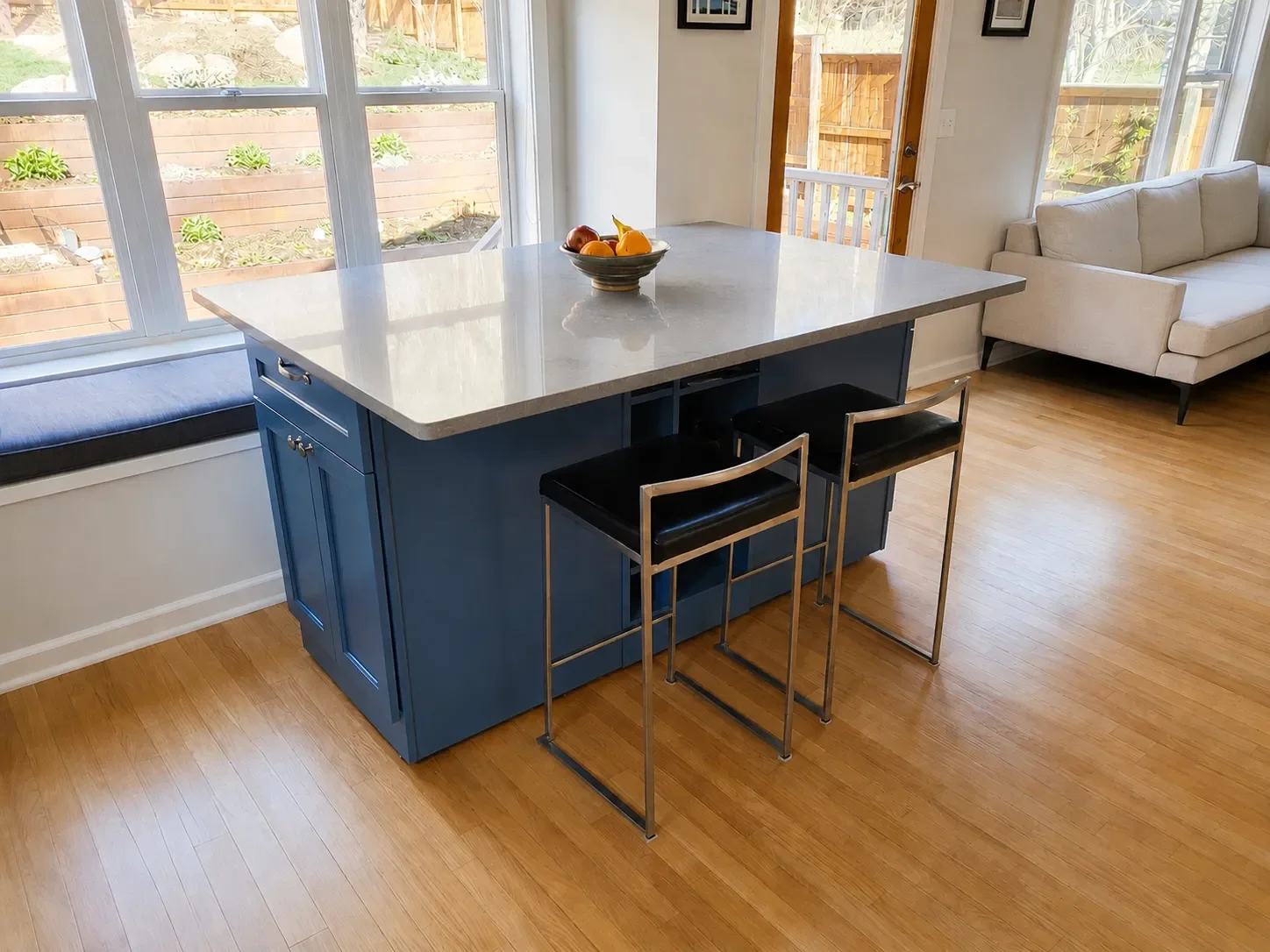 Completed custom mobile kitchen island in Superior, CO featuring gray countertop with overhang for bay window nook seating and additional barstool seating, with additional kitchen cabinet, drawer, and shelf storage