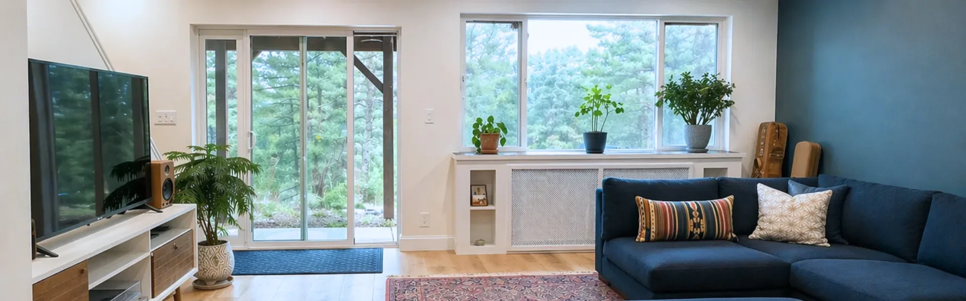 Finished mountain walkout basement remodel in Seven Hills, Boulder, CO showcasing sliding glass patio doors, mountain views, grated radiant heat shelving unit, and furnished living room entertainment area