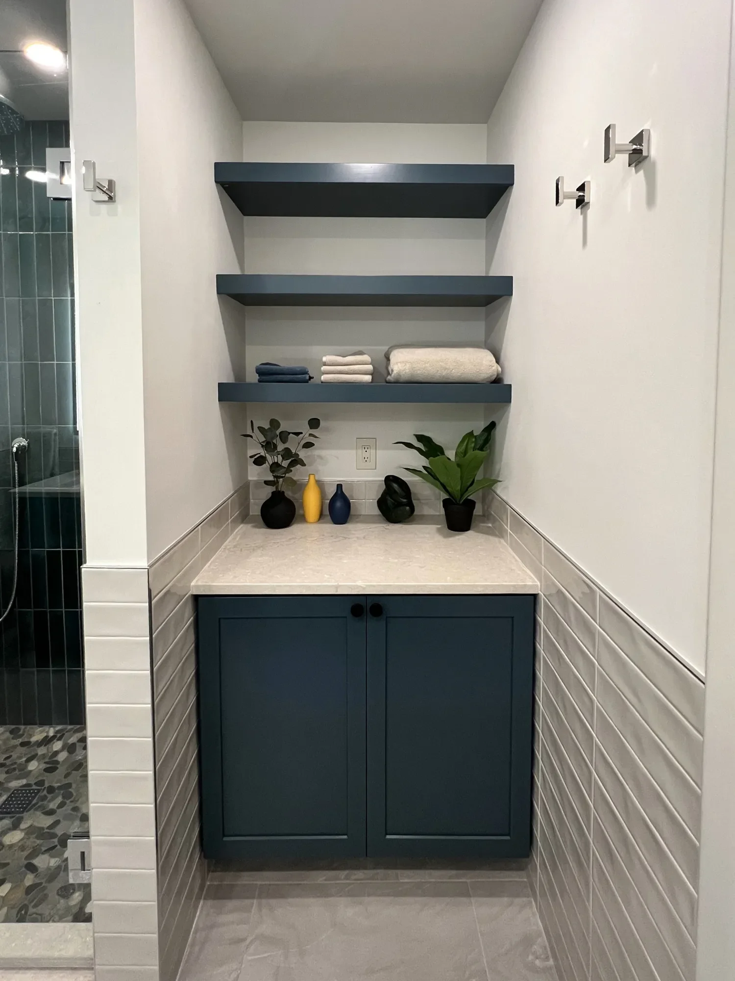 Chautauqua, Boulder, CO close-up of custom bold blue cabinet storage with floating shelves, quartz countertops, and beige tile wainscoting in a completed bathroom remodel in the Chautauqua neighborhood of Boulder, CO