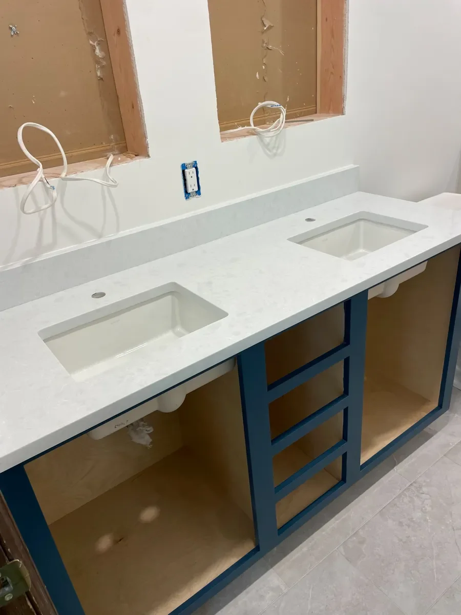 View of partially installed custom blue double vanity with white quartz countertop in an unfinished bathroom remodel in progress in Boulder, CO