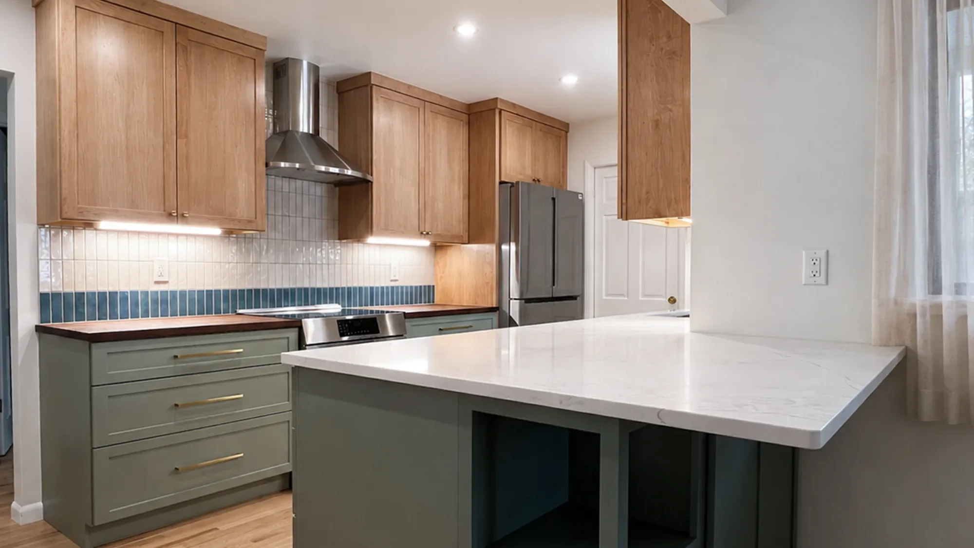 Banner overview of two-tone transitional mixed-material craftsman kitchen in Longmont, CO with white quartz countertop, sage green lower cabinets with open shelf storage, maple upper cabinets, dark walnut countertops, and white tile backsplash