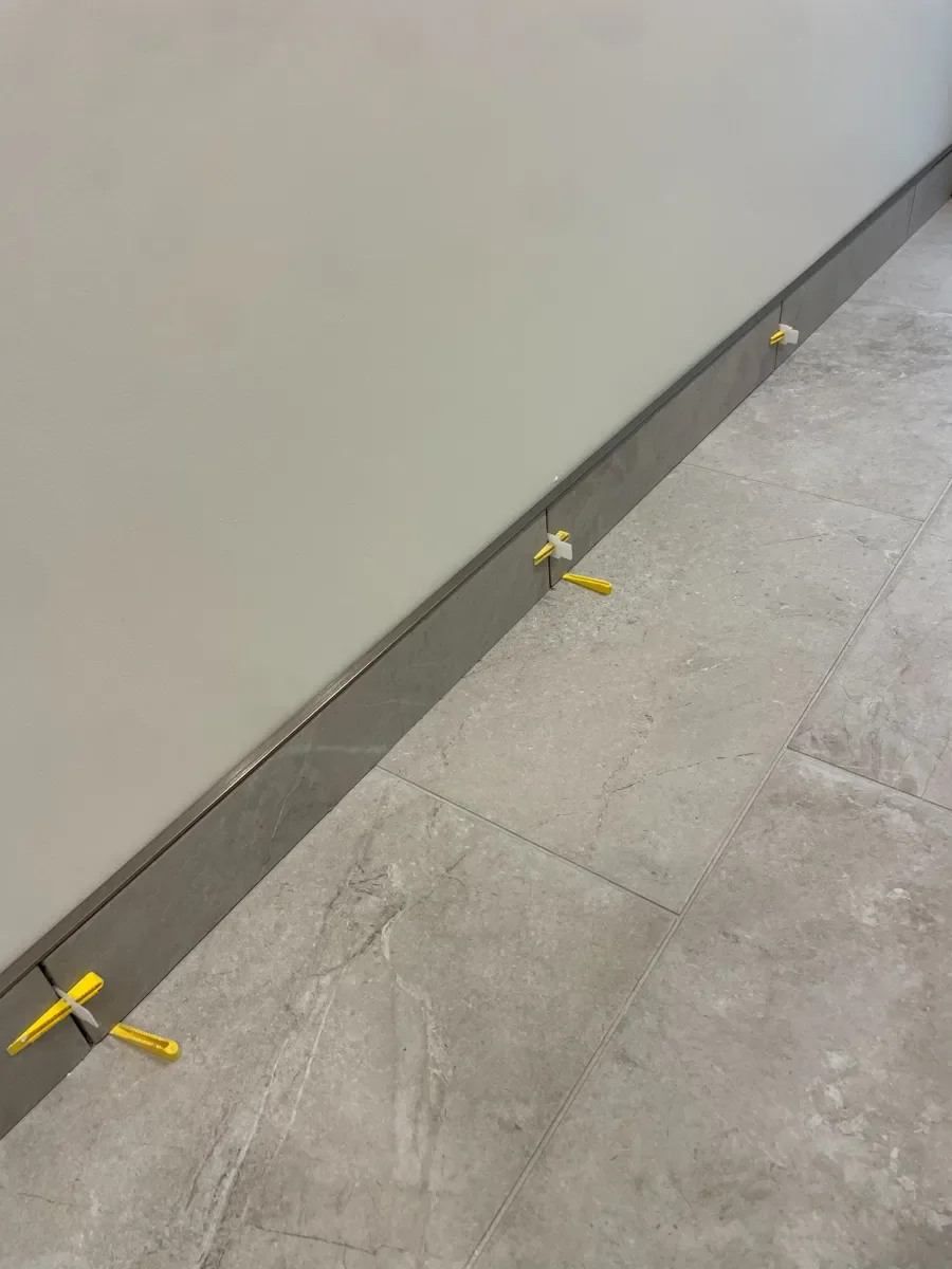 Freshly tiled bathroom baseboards drying with spacers in a Boulder, CO bathroom remodel in progress