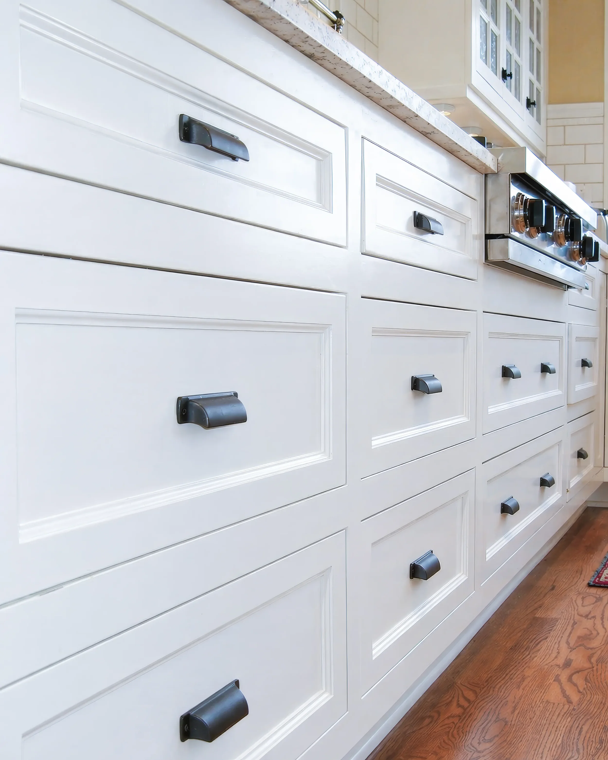 Detail view of white handcrafted cabinets with inset drawers and matte black pull handles in a contemporary craftsman kitchen remodel in Boulder, CO