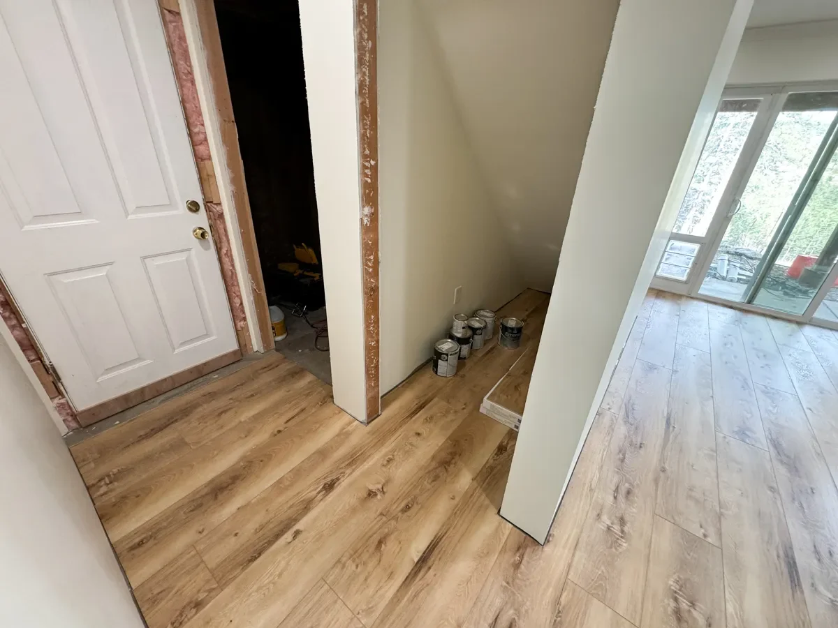 Seven Hills, Boulder, CO walkout mountain basement remodel, view of process laying vinyl plank flooring underneath future under staircase storage closet