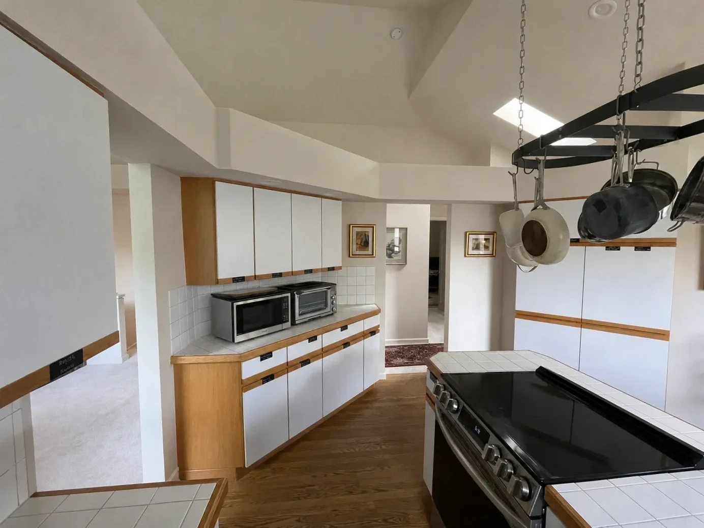 Kitchen in Gunbarrel, CO before remodel, with limited counter space, island stove placement, and outdated wood cabinets with white laminate panel doors