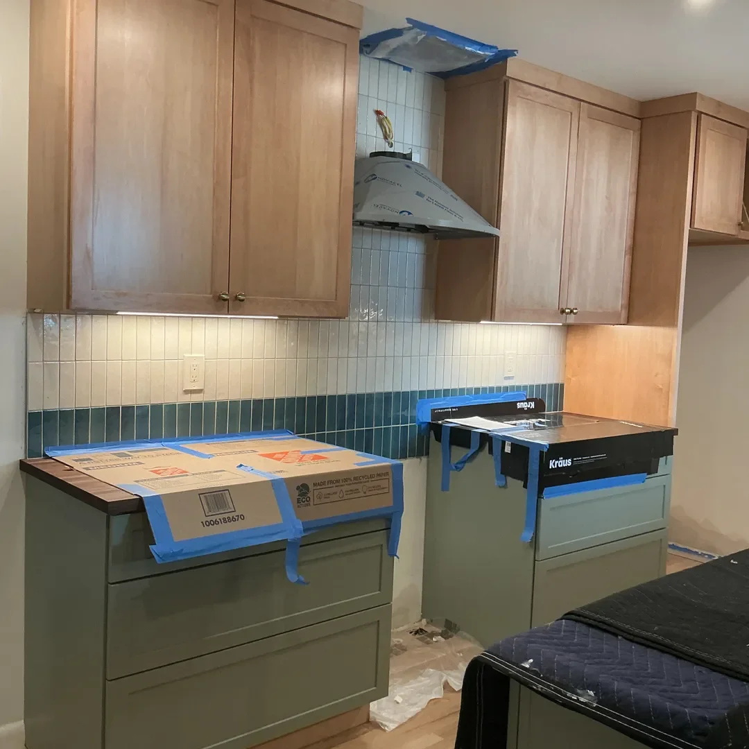 Freshly tiled full height white and teal backsplash and partially installed stainless steel range hood with opening in ceiling for new ventilation system in a Longmont, CO kitchen remodel in progress.