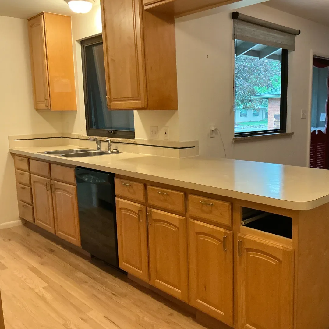 Kitchen awaiting remodel in Longmont, CO with honey-stained cabinets, laminate countertops, and a broken drawer