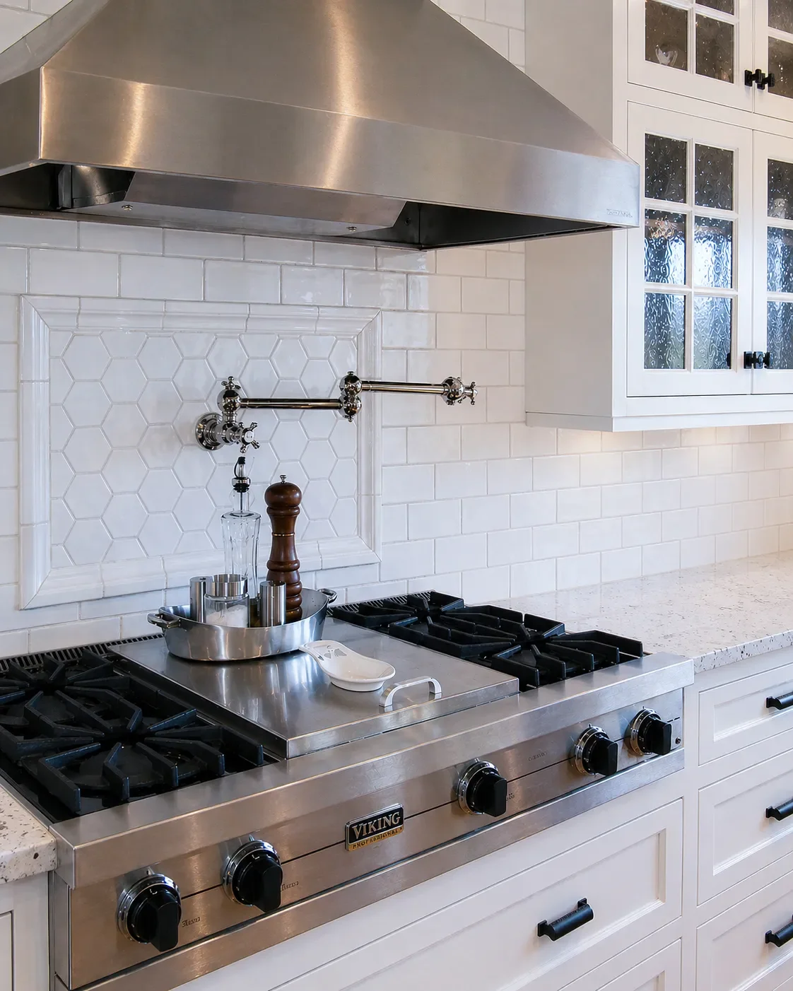 Modern kitchen with tile backsplash, stainless steel appliances, wooden cabinets, island with white countertop, red pendant lights, and bar stools.