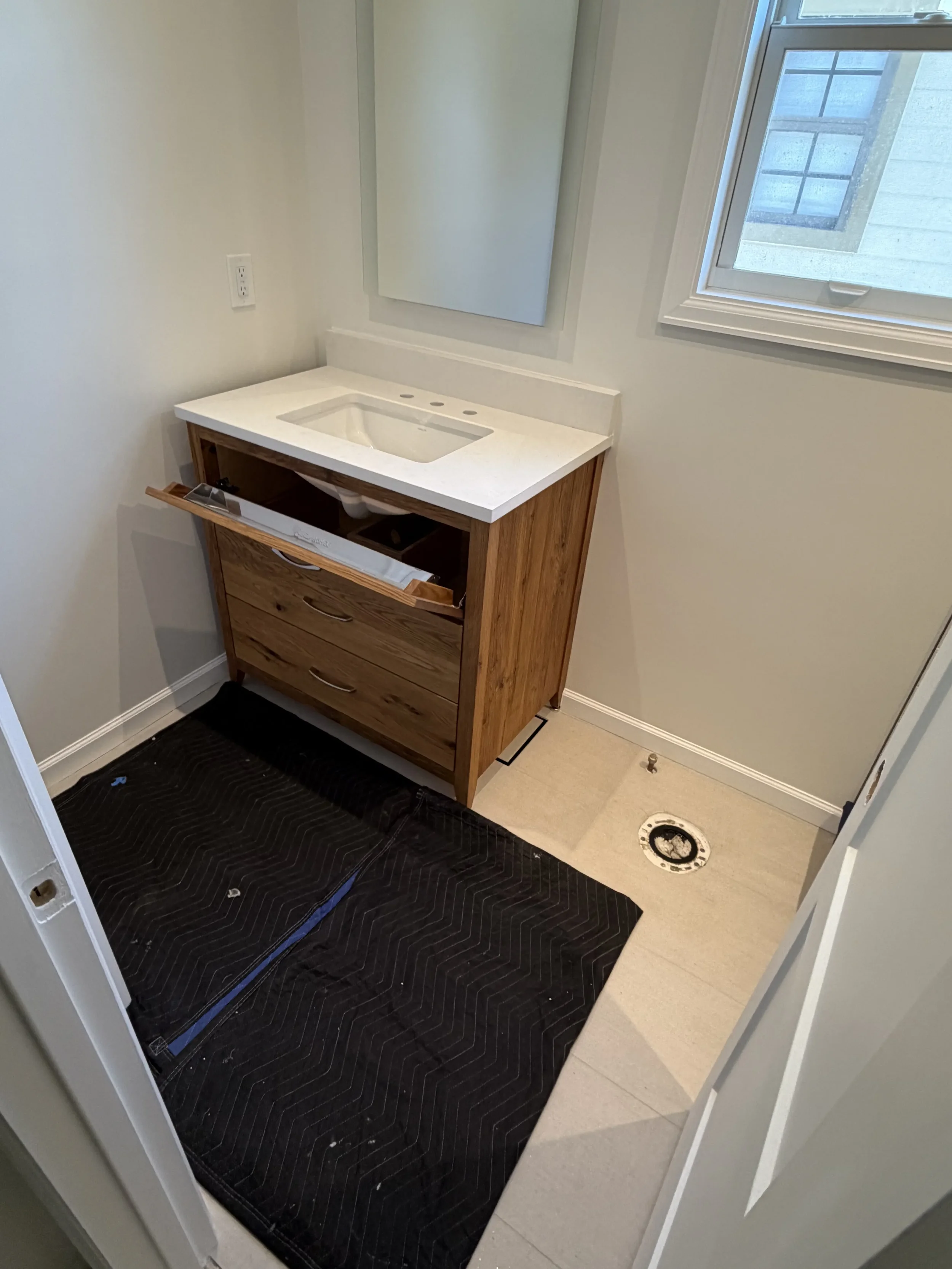 Unfinished bathroom remodel in progress featuring newly tiled floors and partially installed reclaimed barnwood vanity in Boulder, CO