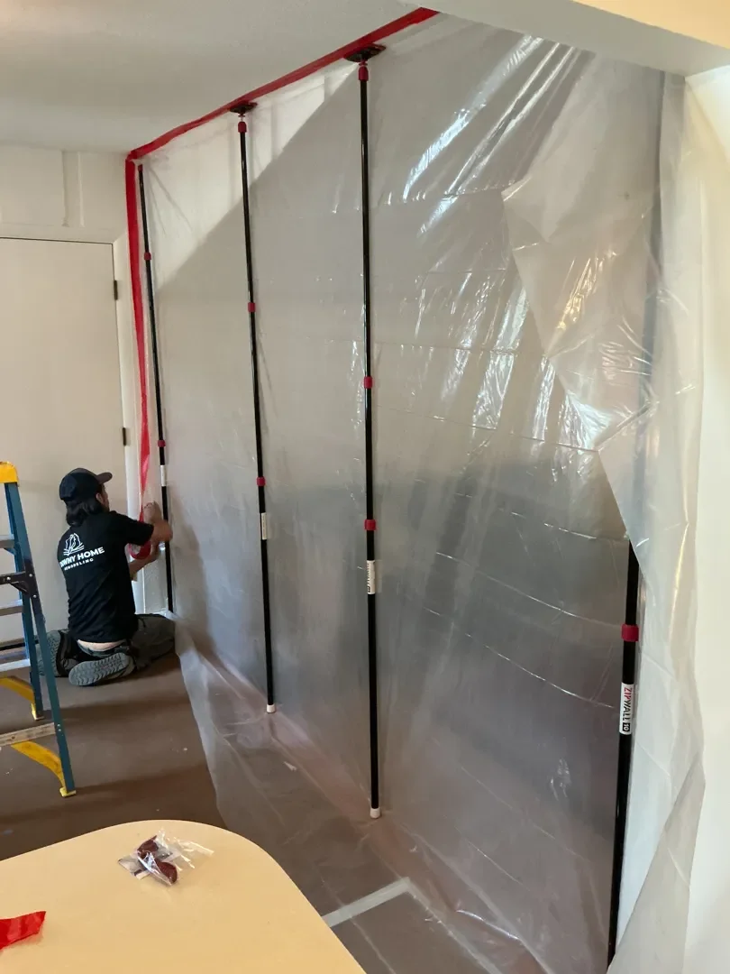 Employee at Downy Home Remodeling taping off the sides of a plastic dust protection barrier at client's Longmont, CO home, preparing for kitchen demolition