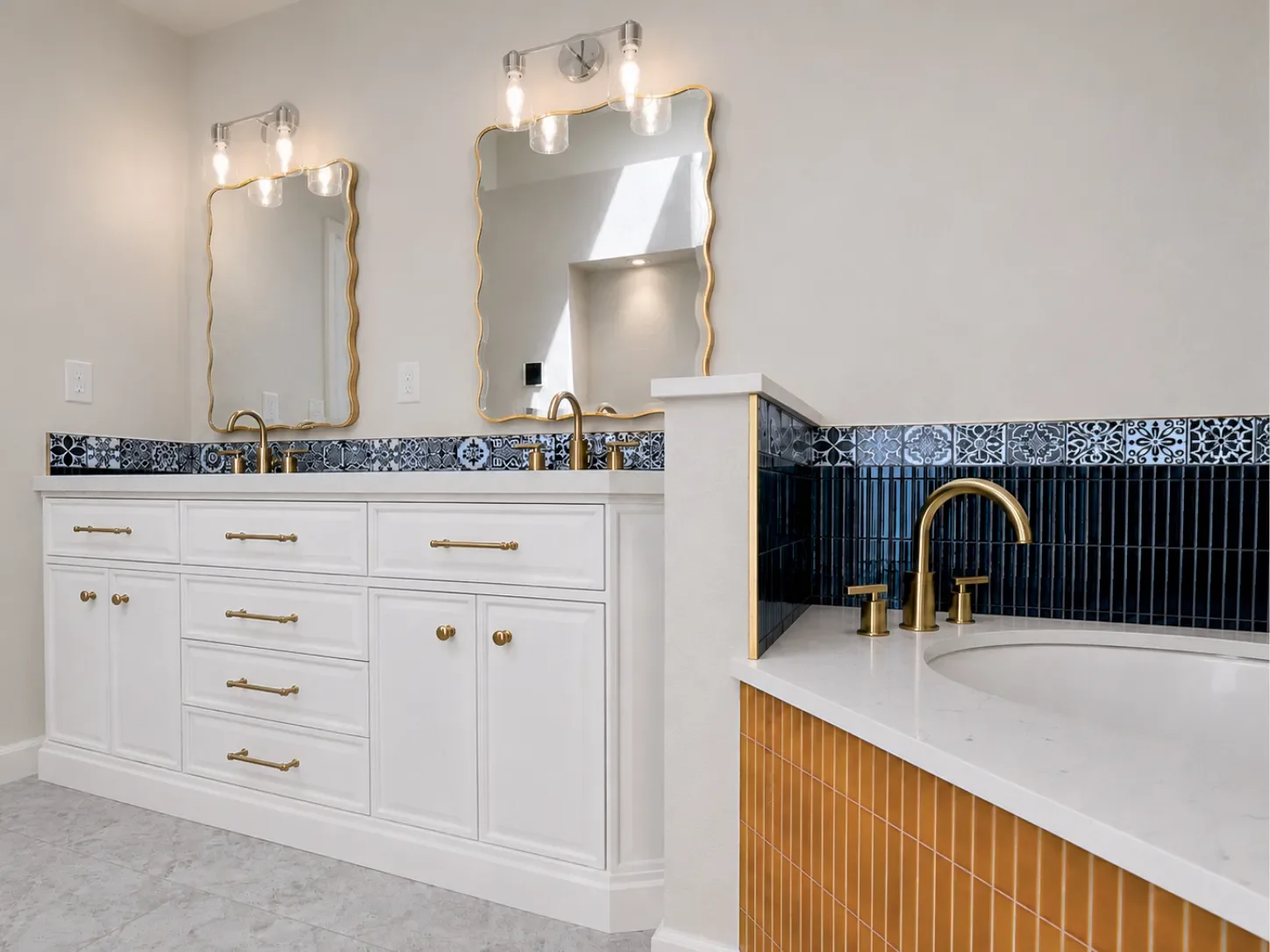 Completed Gunbarrel, CO contemporary art deco master bathroom remodel with white vanity, scalloped gold edge mirrors, soaking tub, blue and gold bold contrast tile, and gold fixtures