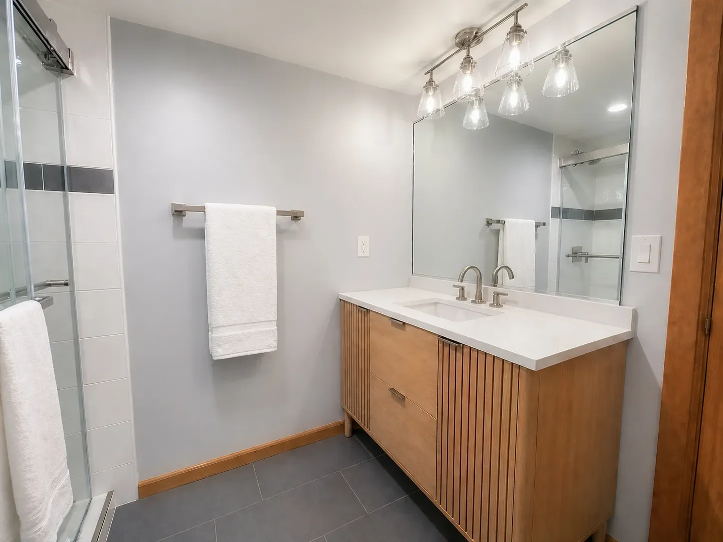 Custom standing oak vanity and glass walk-in shower with powder blue walls in a contemporary, minimal, budget bathroom remodel in Niwot, CO