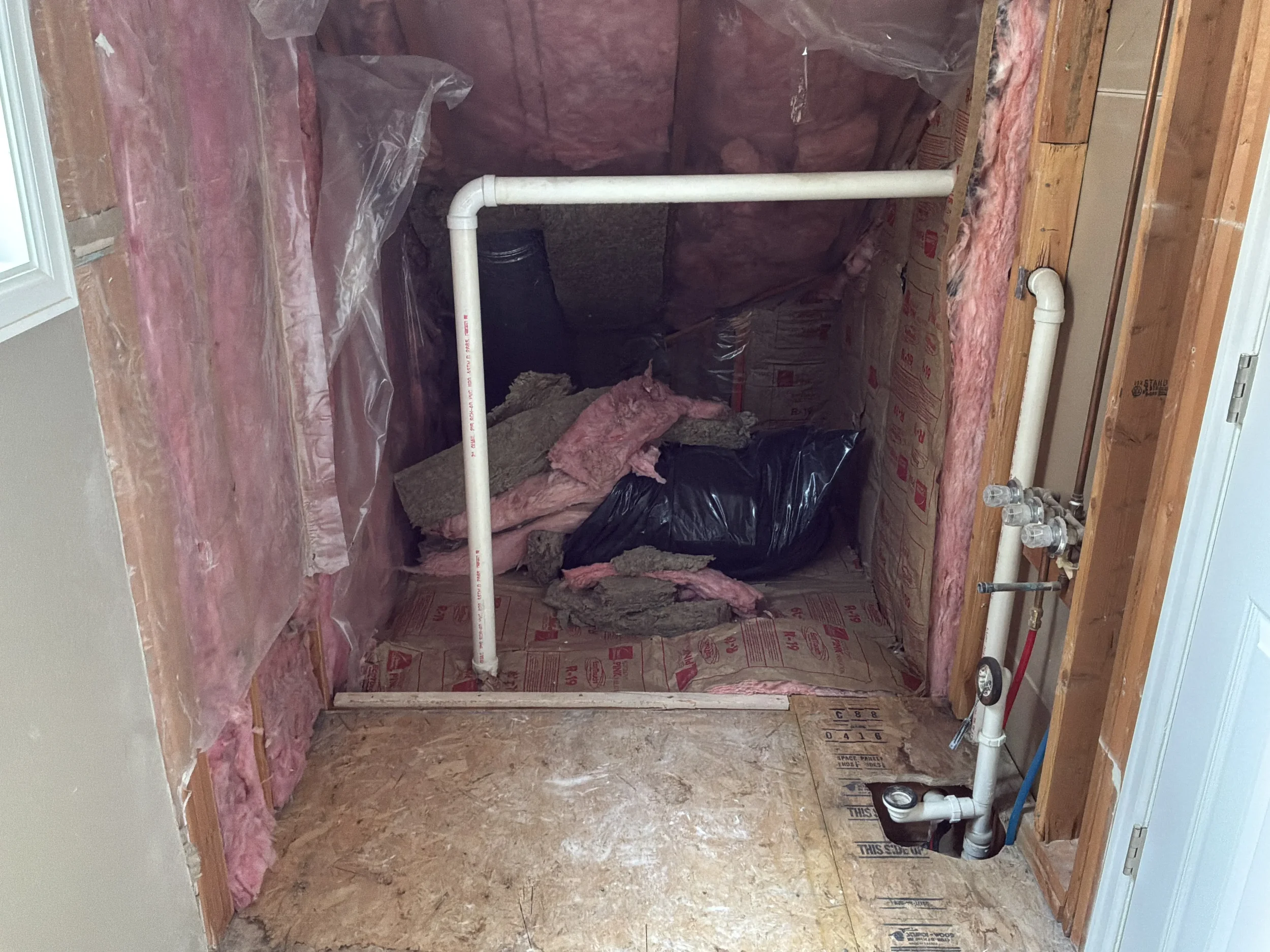 Gutted bathroom during demolition in a Boulder, CO bathroom being remodeled by Downy Home Remodeling, no walls or floor, exposed plumbing and insulation.