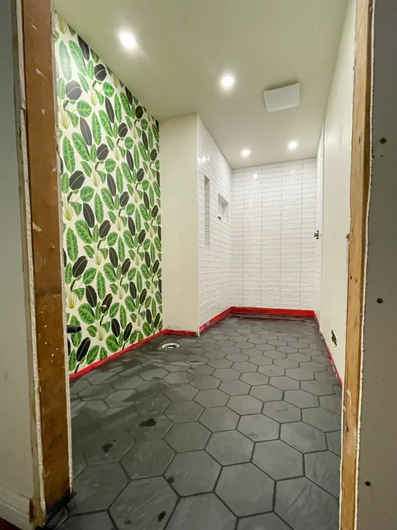 Progress photo of bathroom remodel in Superior, CO nearing completion with green leaf wallpaper accent wall