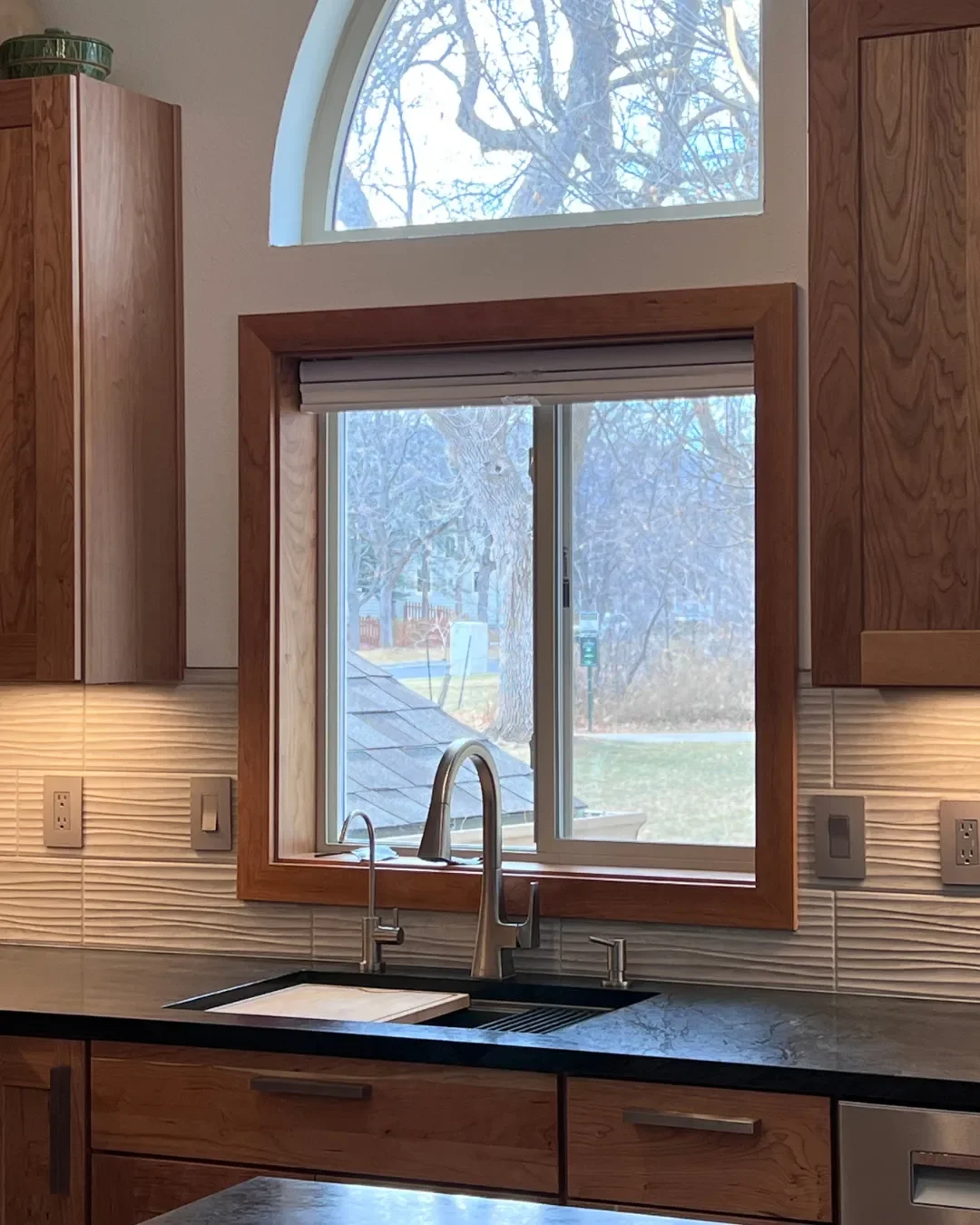 Close up of window behind sink framed with cherry wood trim in a completed craftsman kitchen remodel in Newlands Boulder, CO