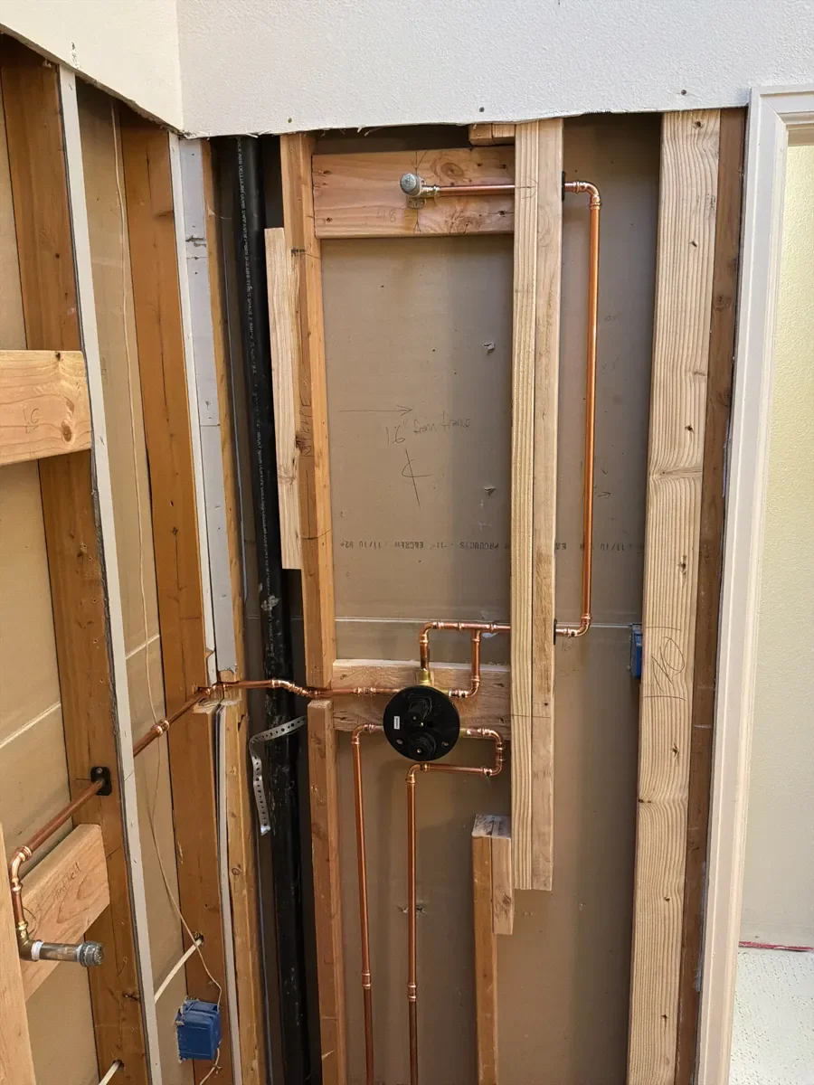 Reconfigured copper pipe plumbing inside the wall frame of a bathroom remodel in progress in Gunbarrel, CO