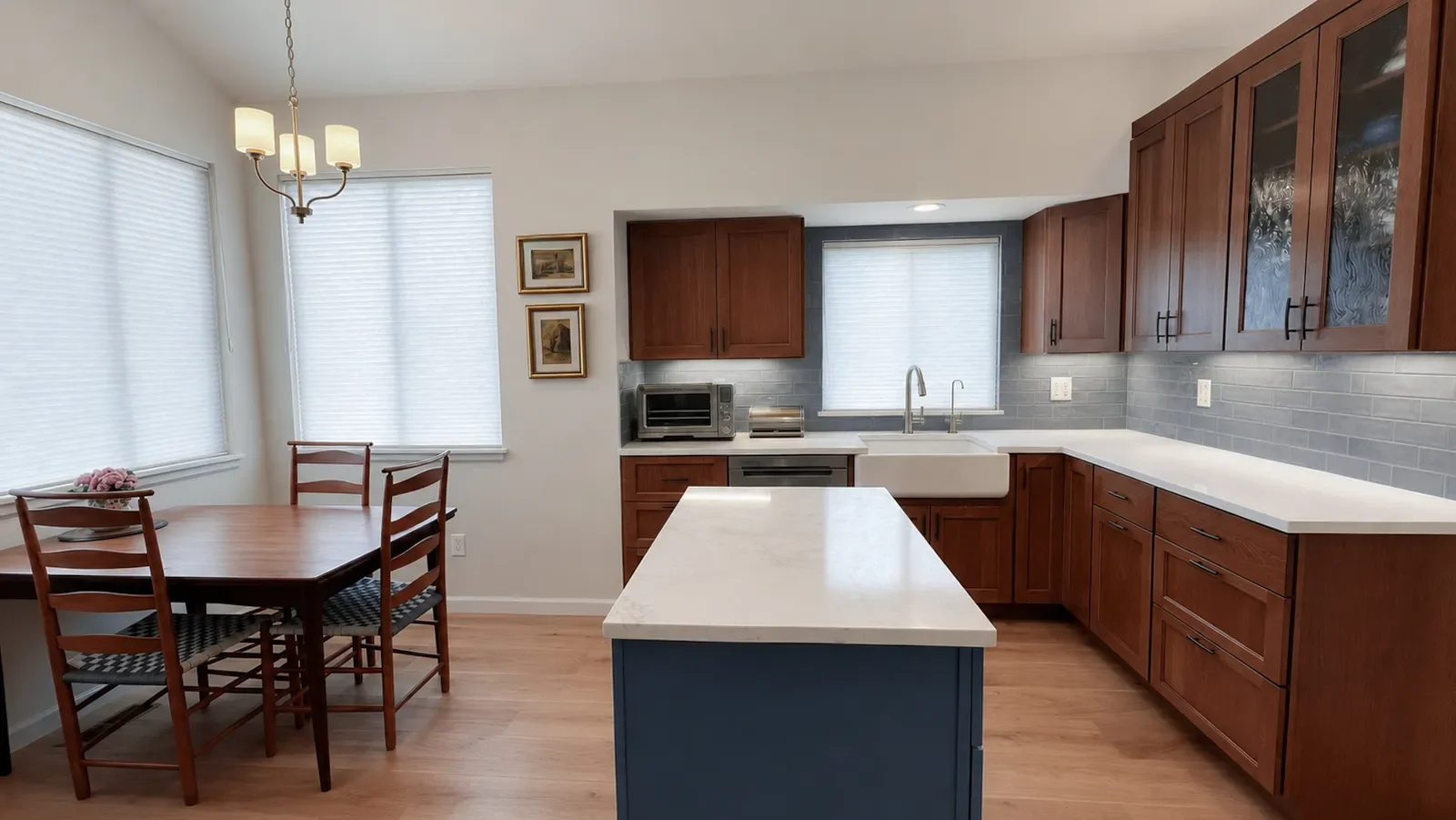 View of white farmhouse sink and custom cherry wood cabinets with LED underlighting and blue mobile island on casters with white quarts countertop in a Gunbarrel, CO kitchen remodel
