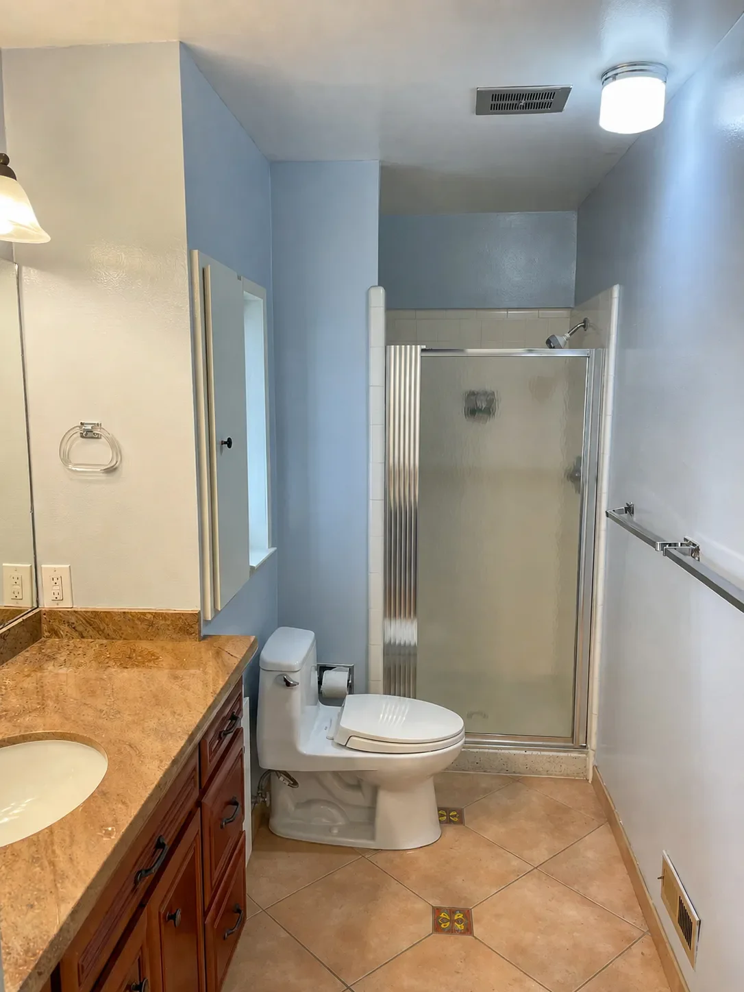 Retro bathroom before remodel in Superior, CO with brown tiled floor, brown countertops, and baby blue walls in Superior, CO
