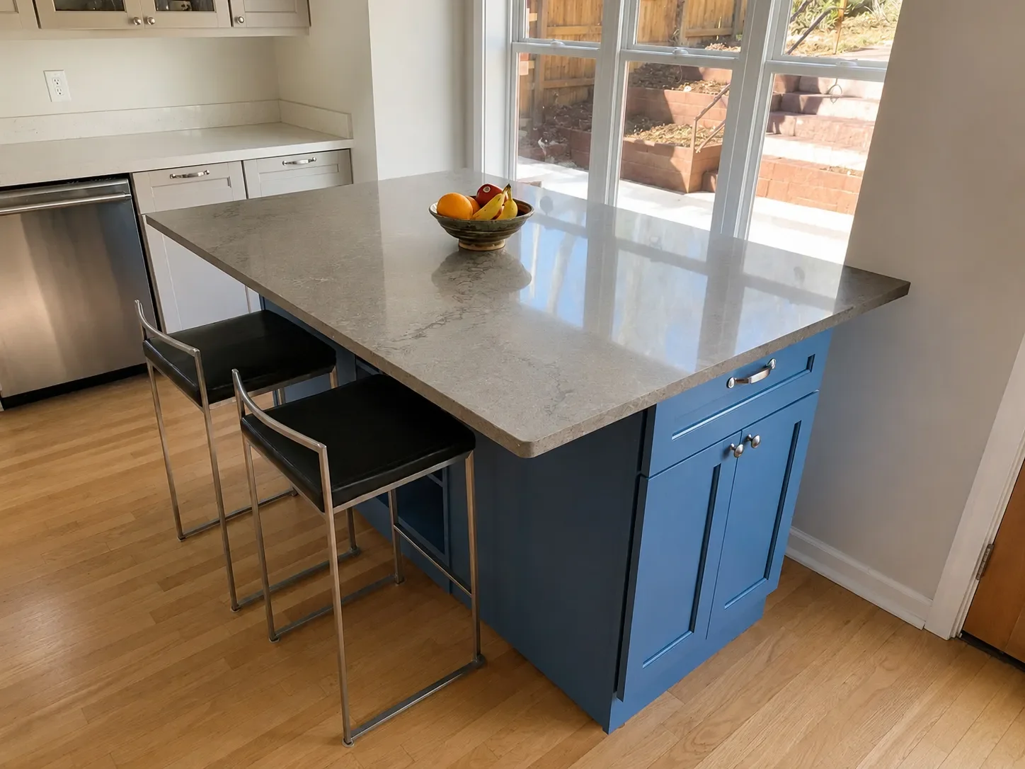 View of blue custom mobile kitchen island with gray quartz countertop and 12" overhang too accomodate barstool seating and bay window breakfast nook seating in Superior, CO