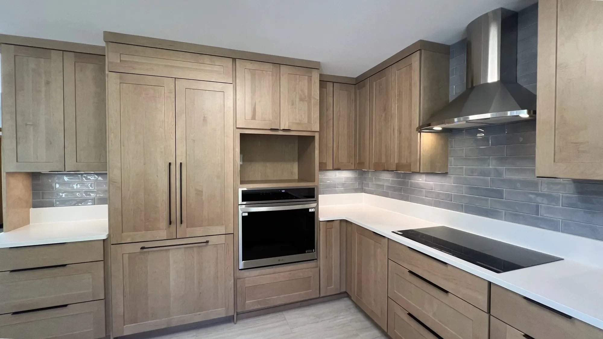 Craftsman kitchen with custom oak cabinets, light blue subway tile, concealed fridge cabinet door panels, and stainless steel appliances, remodeled by Downy Home Remodeling