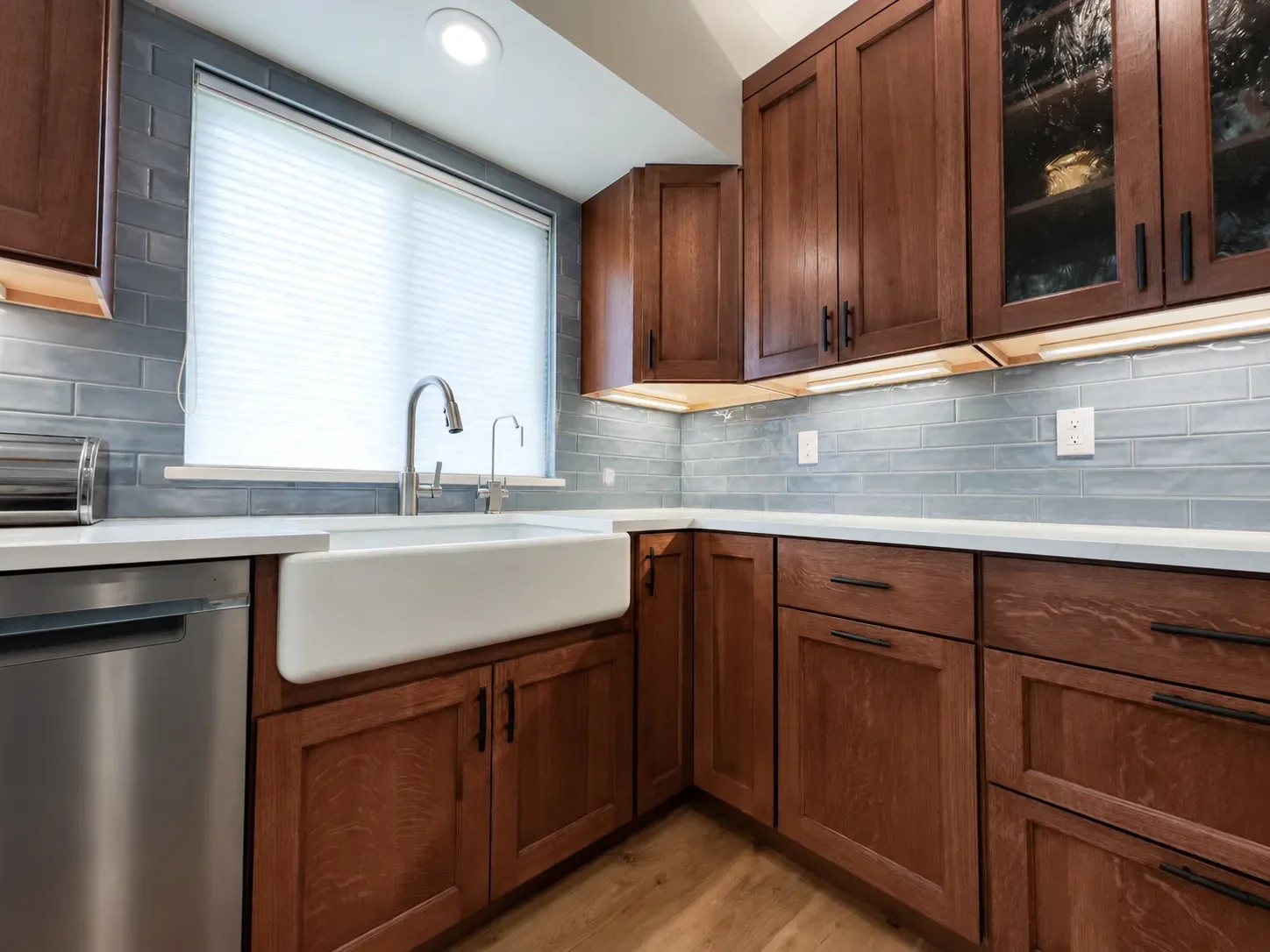 Gunbarrel, CO contemporary craftsman kitchen remodel with custom cherry cabinets, white farmhouse undermount sink, white quartz countertops, oak hardwood flooring, and light blue subway tile backsplash