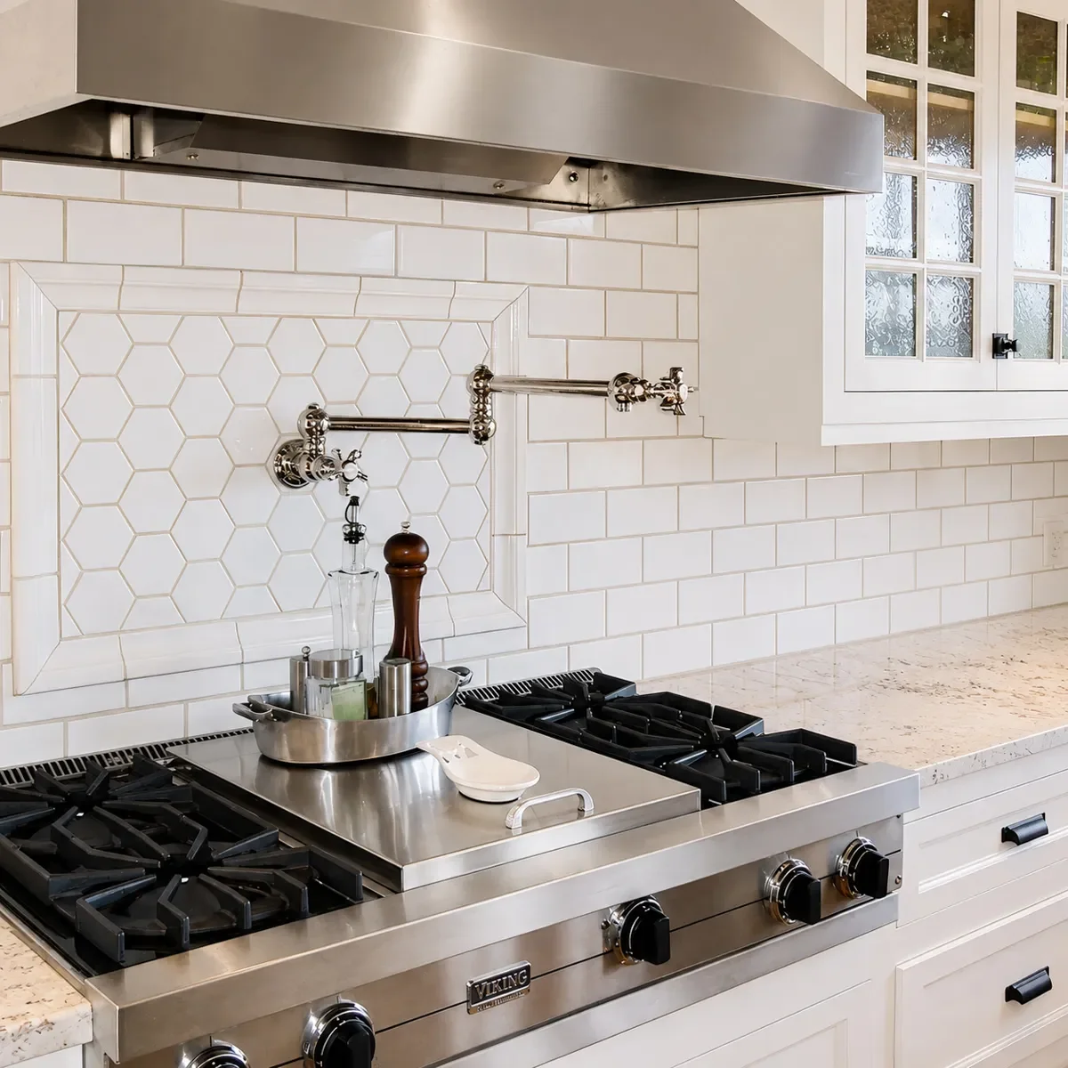 Detail shot of luxury high end stainless steel gas stove range and wall-mounted pot filler with white inset tile backsplash in a Tudor historic kitchen remodel in the Mapleton Hill district of Boulder, CO