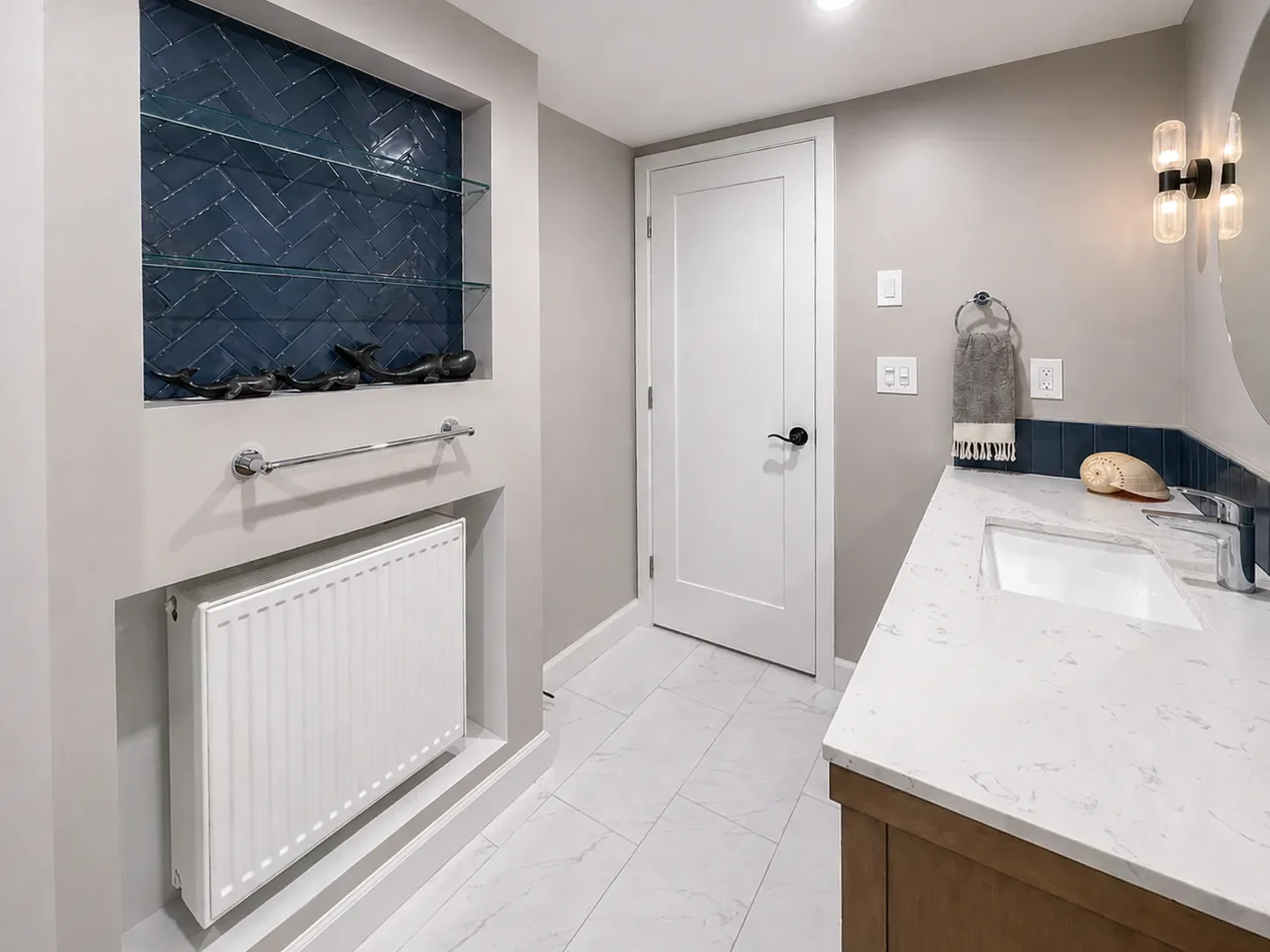 Modern bathroom with white countertop, blue tile shelf, towel rack, and decorative elements like candles and a seashell.